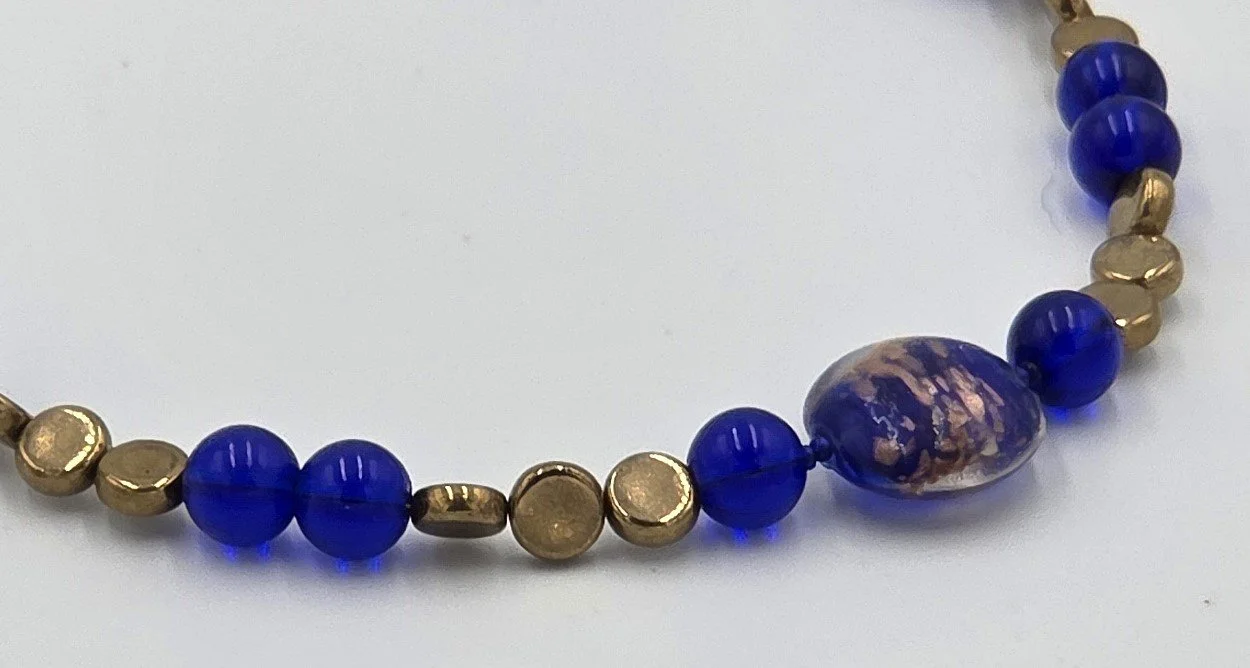 close up of Dark blue and gold choker necklace with a large gold-foil glass bead