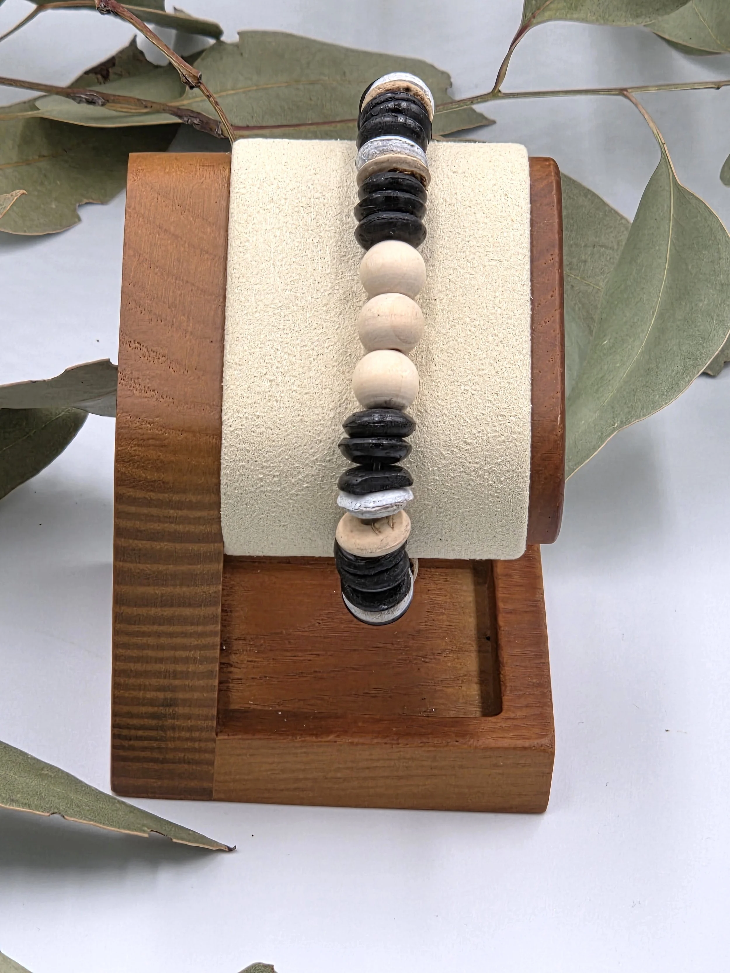 Striped brown and white coconut disc bracelet with three natural raw wood beads as a central focal point.