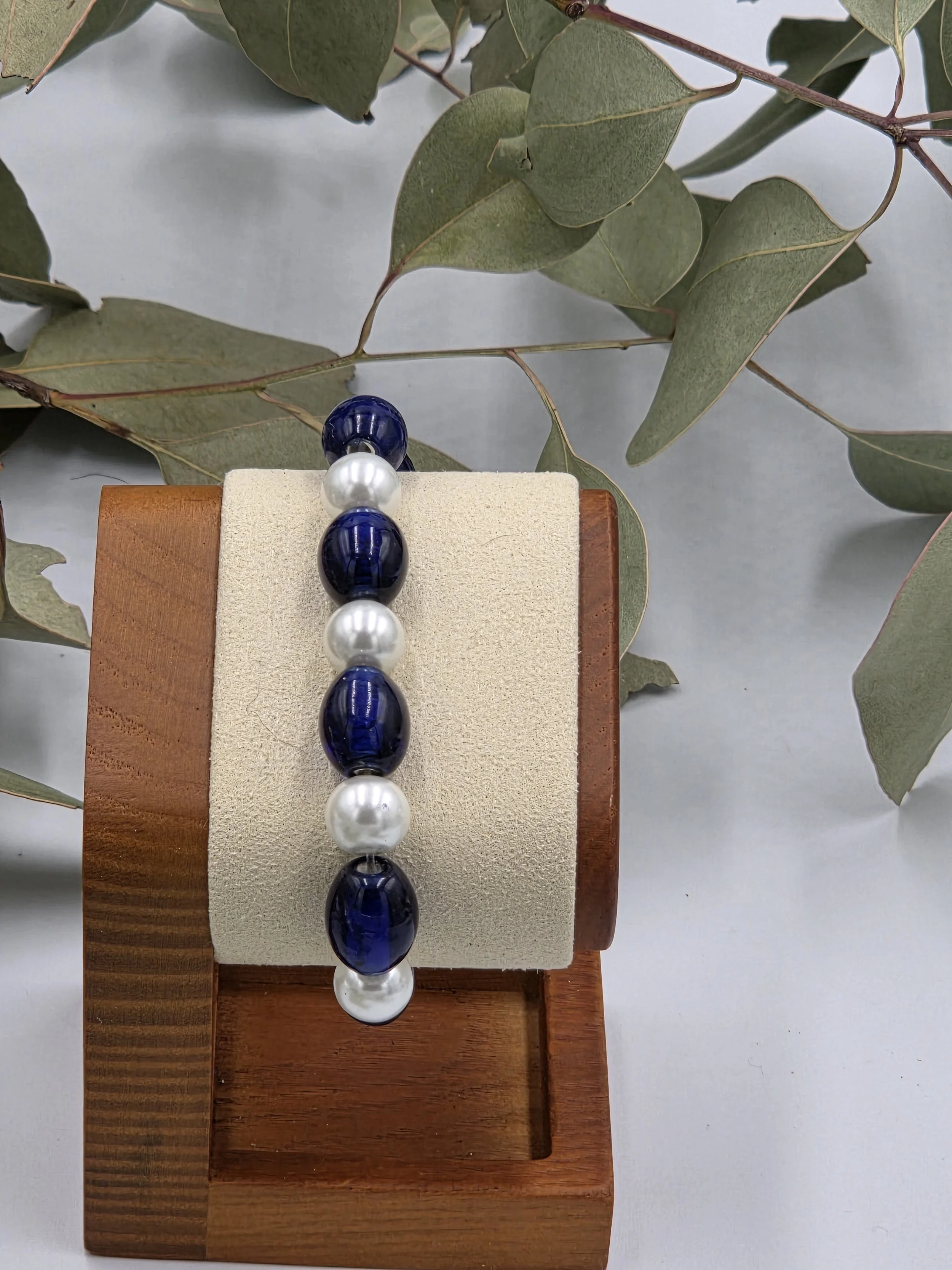 Glossy dark blue oval glass beads alternating with luminous white glass pearls on an elegant elastic bracelet.
