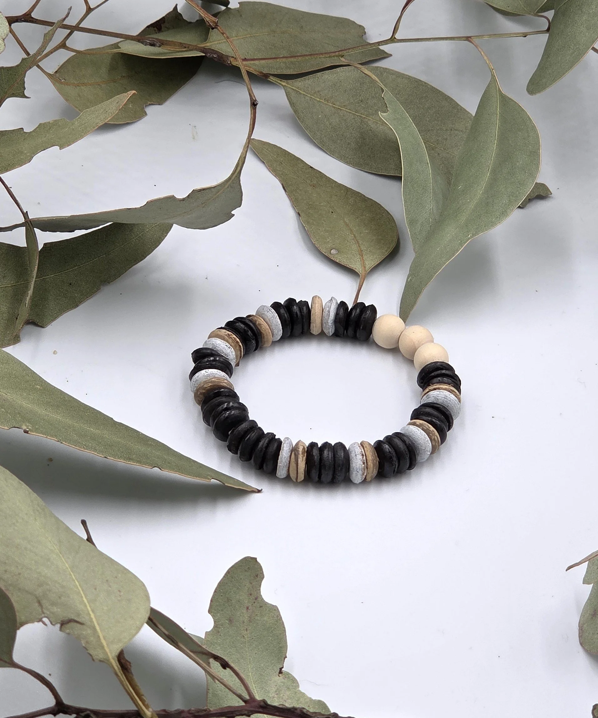 Striped brown and white coconut disc bracelet with three natural raw wood beads as a central focal point.