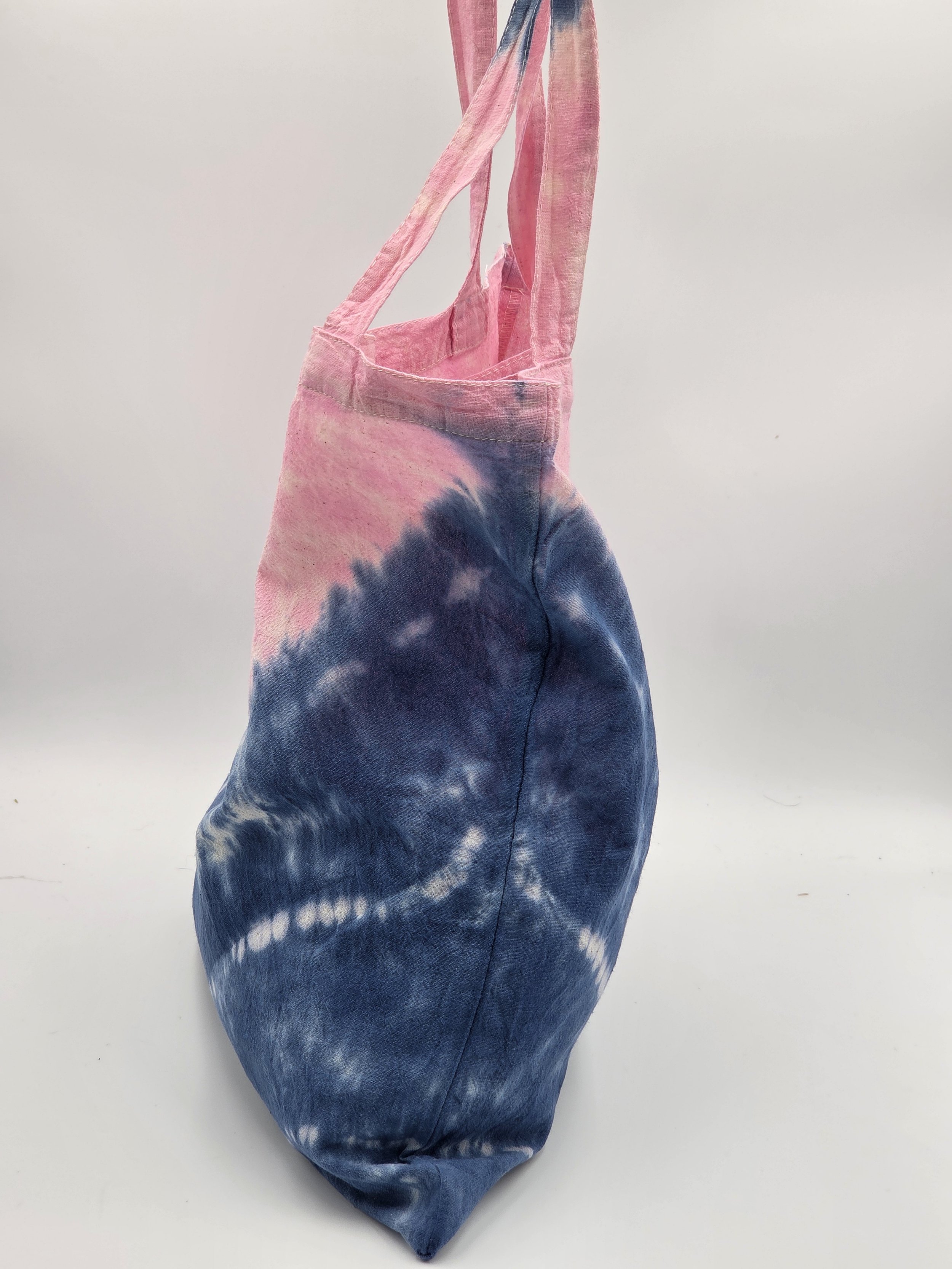 calico tote bag with a diagonal tie-dye split featuring pink on top and dark blue on the bottom with three batik resist lines.