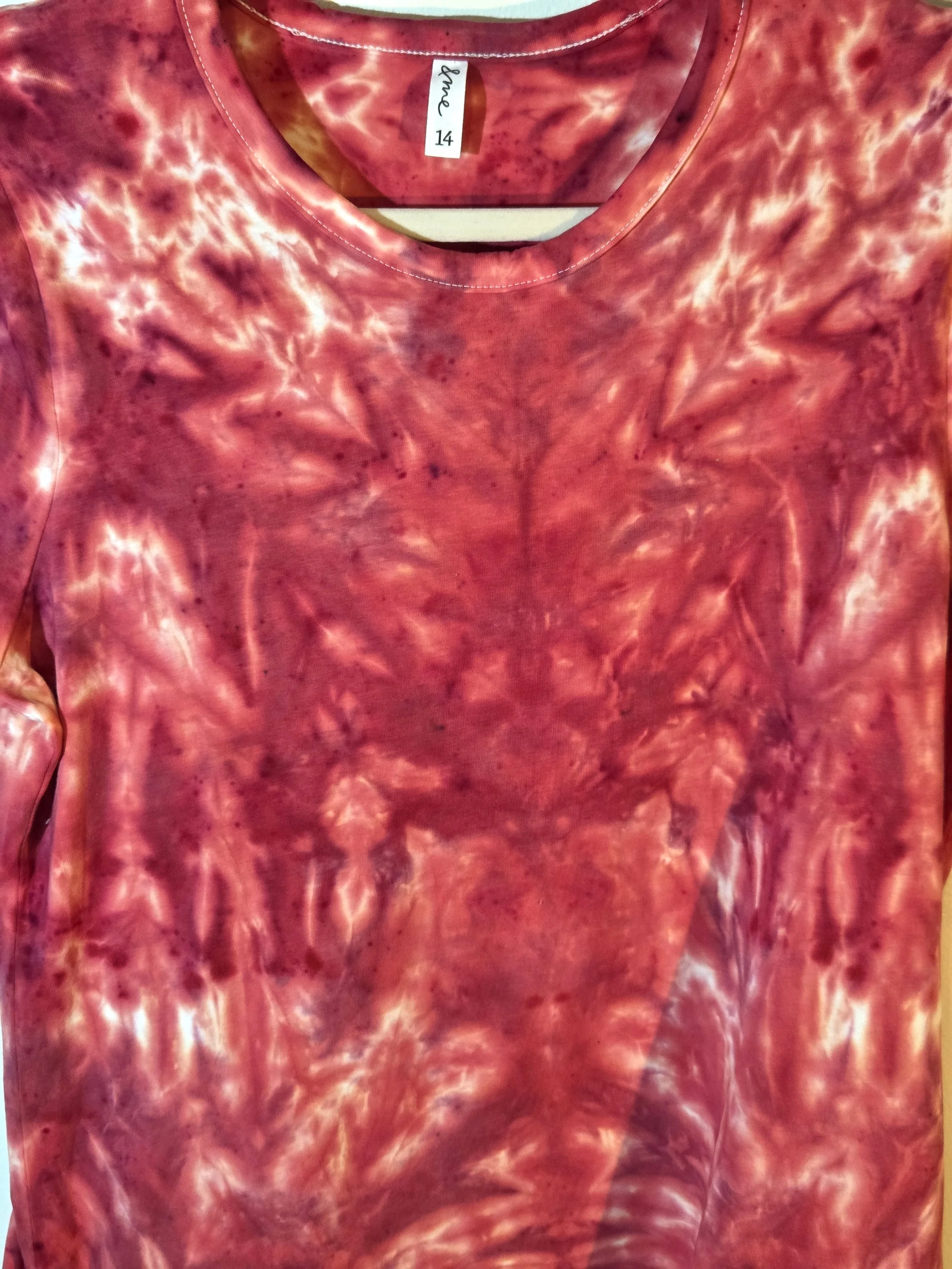 A size 14 women's t-shirt featuring a highly saturated red and coral tie-dye pattern of abstract swirls radiating from the center.