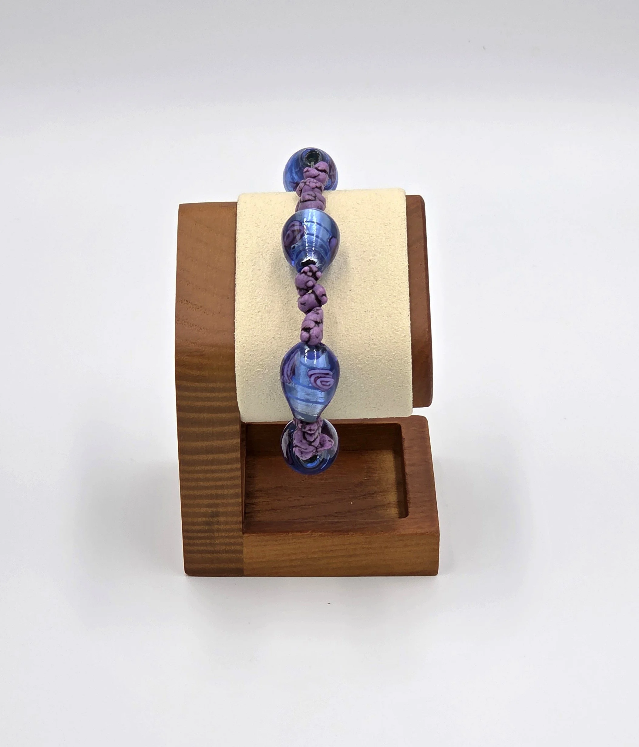 Elastic bracelet with large striped glass beads featuring pink roses and purple stones.