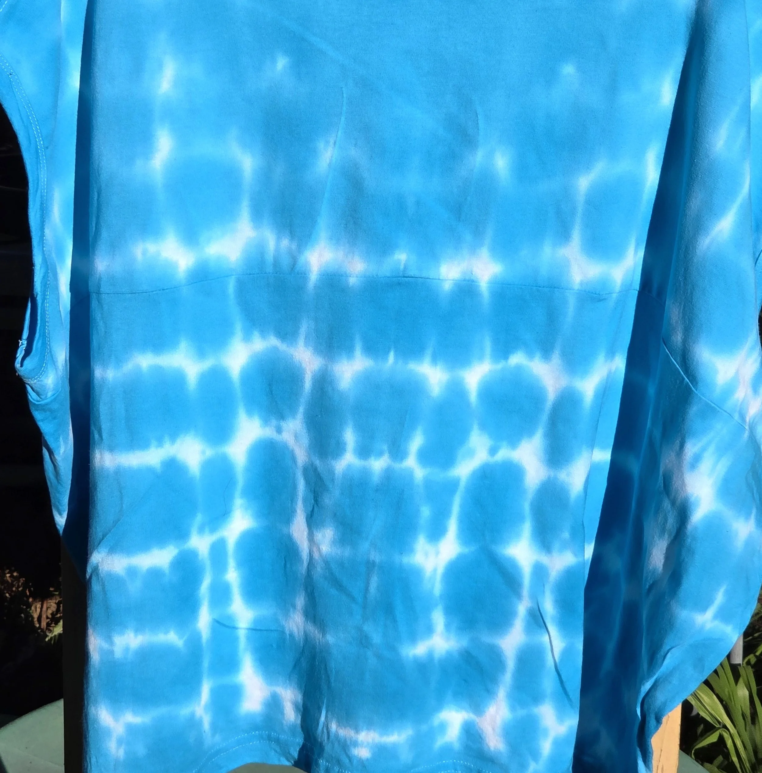 An adult size 12 women's oversized cotton t-shirt featuring a saturated turquoise tie-dye pattern with delicate horizontal white lines.