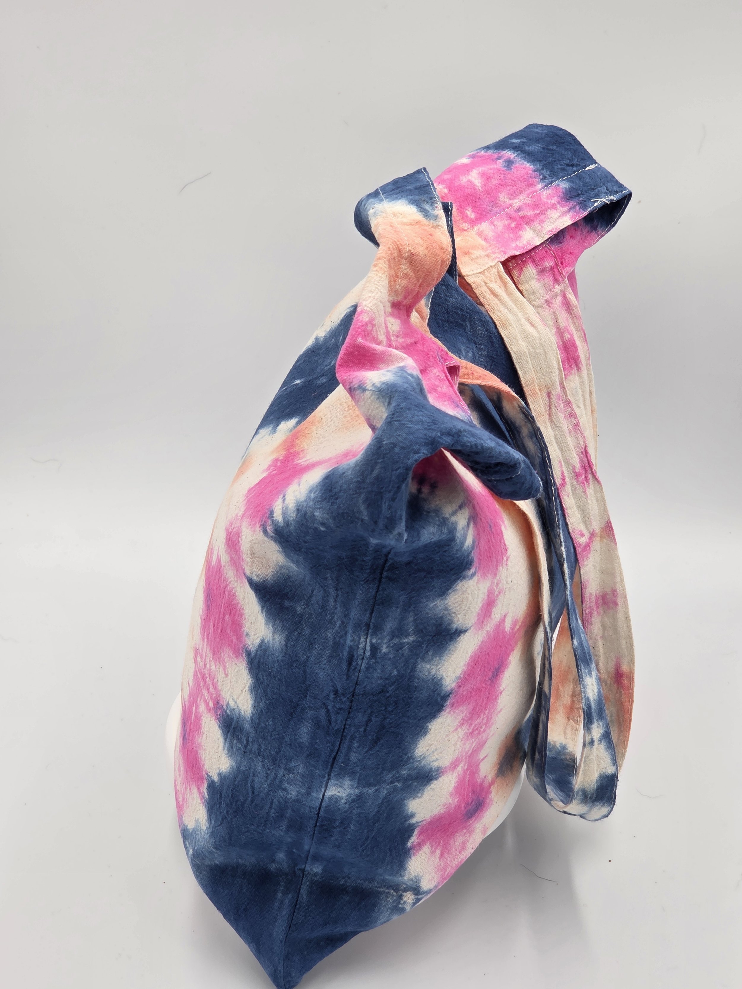 calico tote bag featuring vertical tie-dye columns of dark blue, soft pink, and pale orange with white spaces.