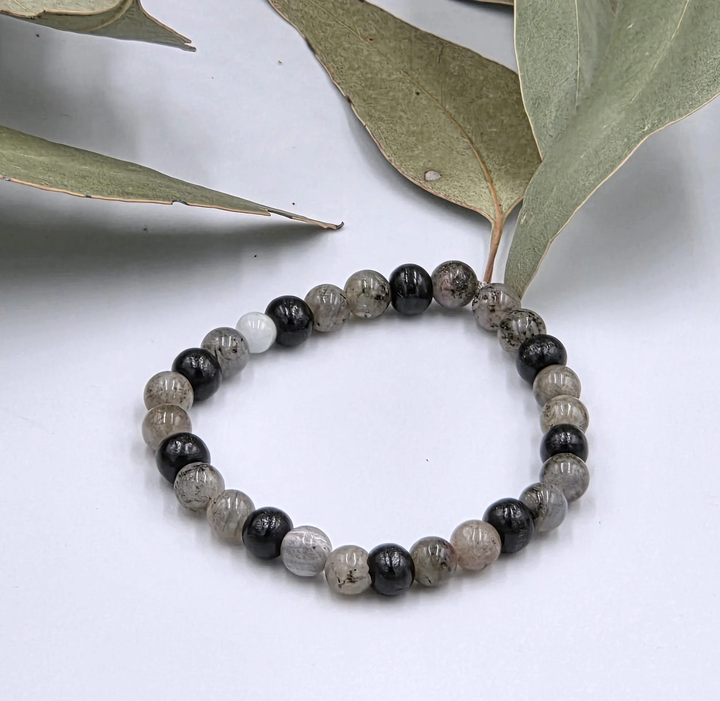 Grey Labradorite beads alternating in pairs with single black wood beads on an elastic bracelet.