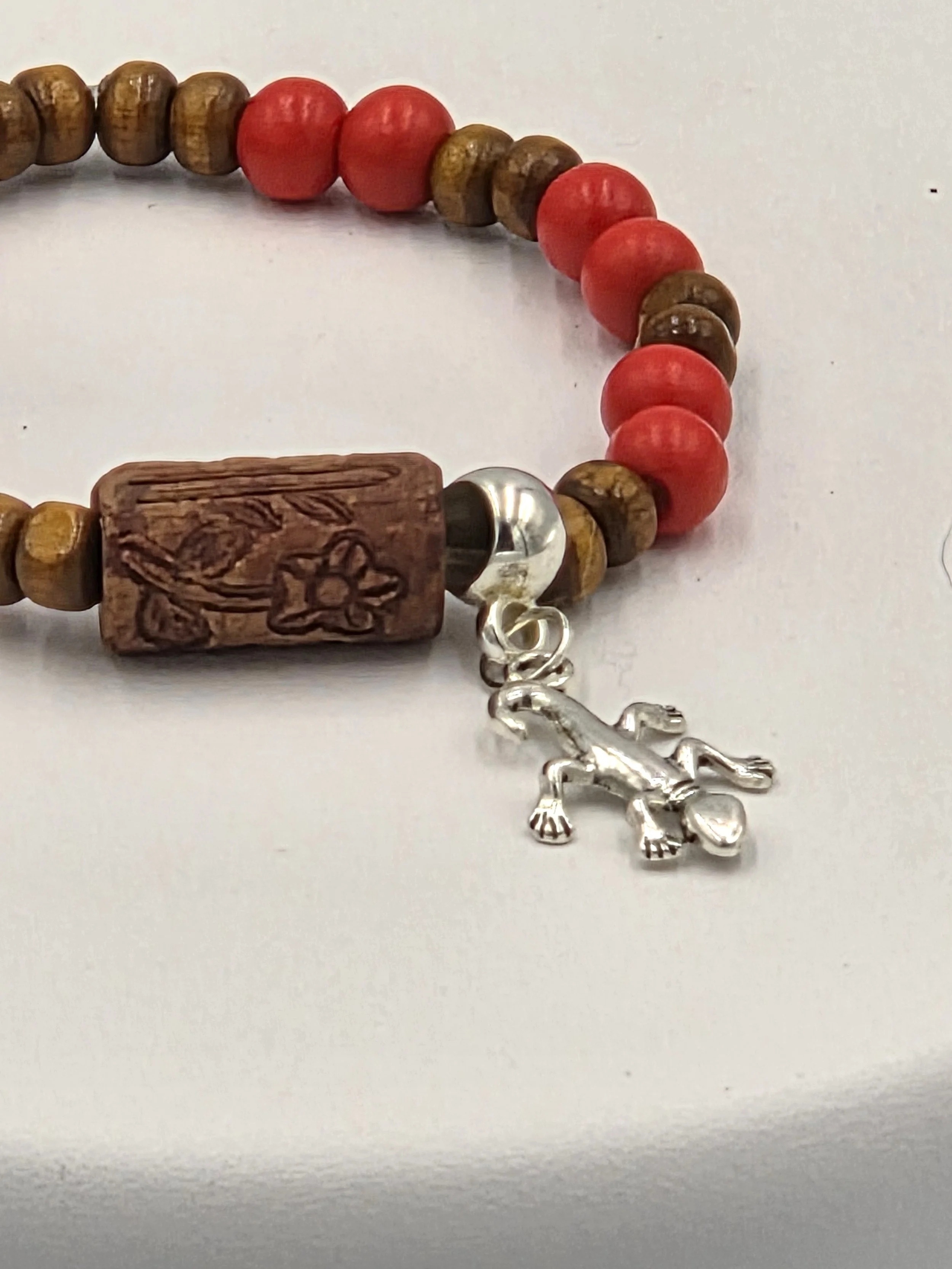 close up of OOAK red and tan wood bracelet with ceramic log bead and silver gecko.