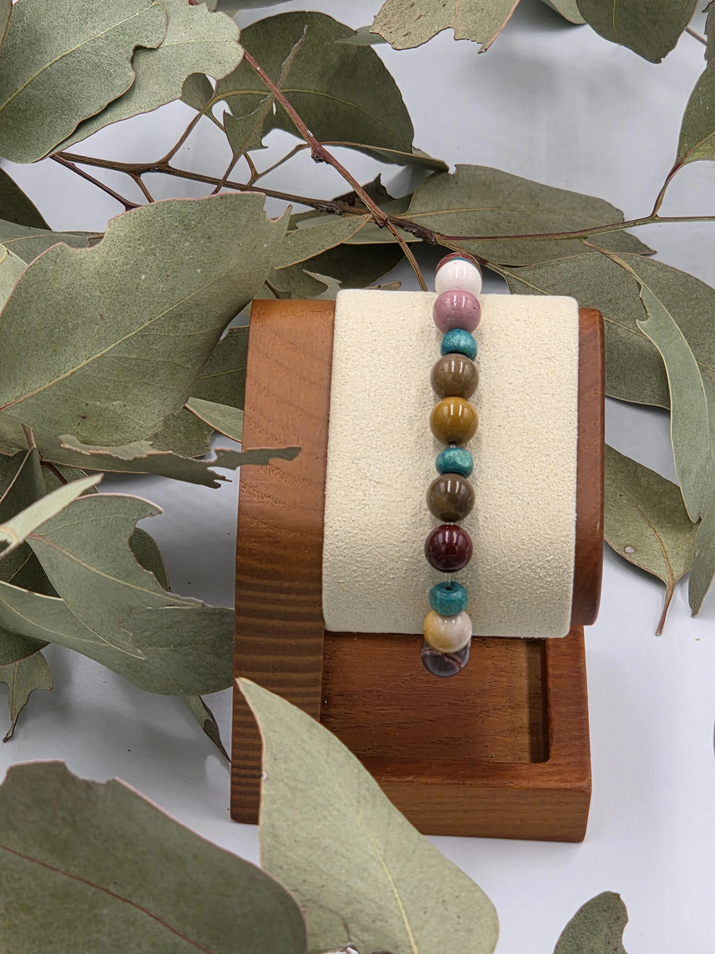 Earth-toned cream and brown Mookaite jasper beads alternating with small sky blue wood beads on an elastic bracelet.