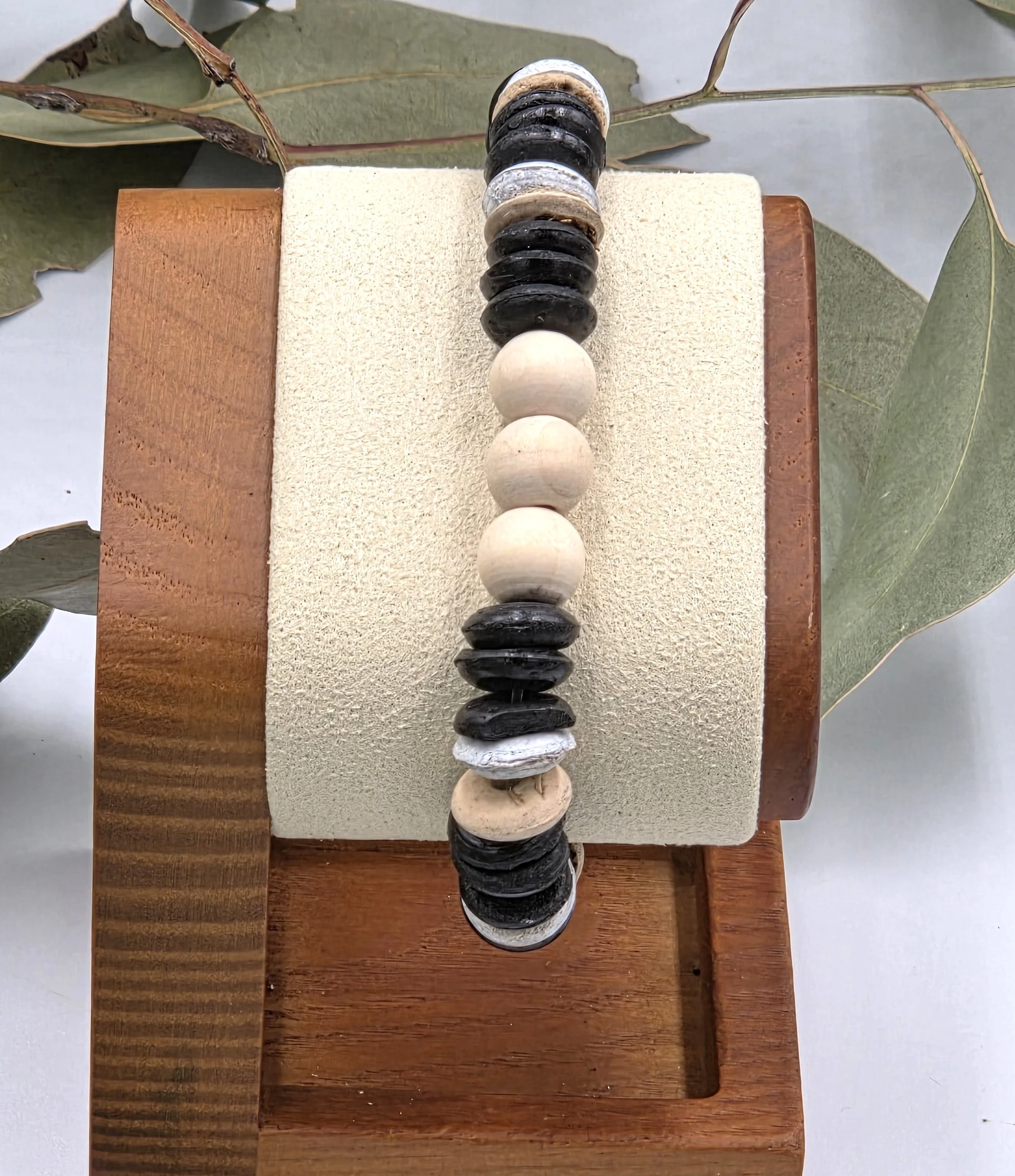 Striped brown and white coconut disc bracelet with three natural raw wood beads as a central focal point.
