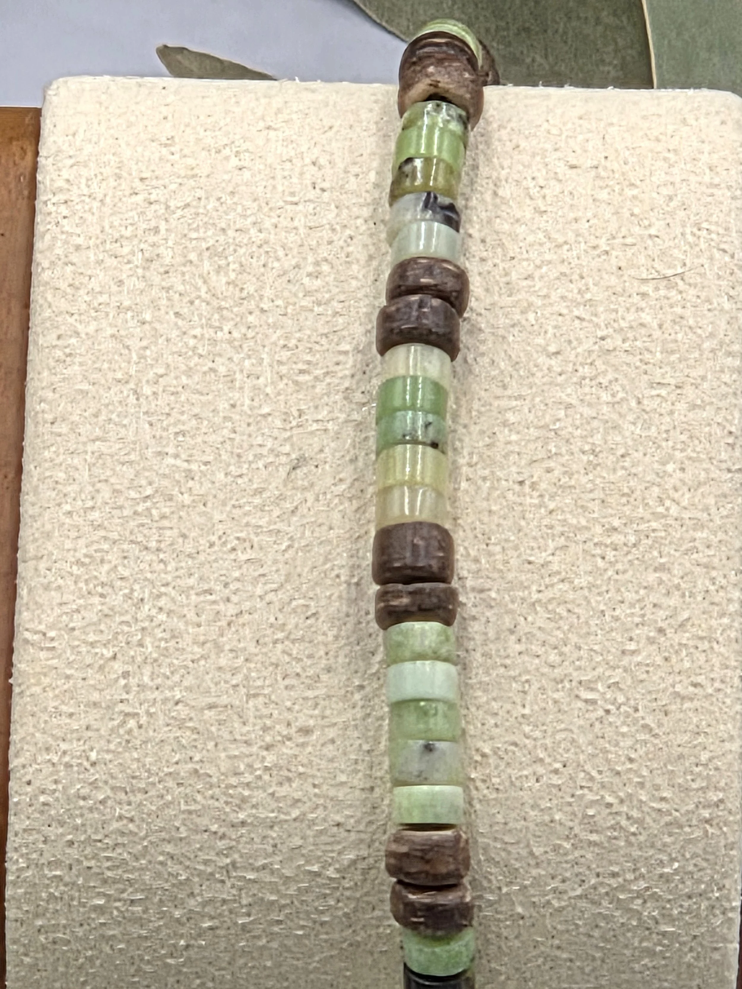 Very small green chrysoprase discs alternating in groups of five with pairs of brown coconut discs on a delicate elastic bracelet.