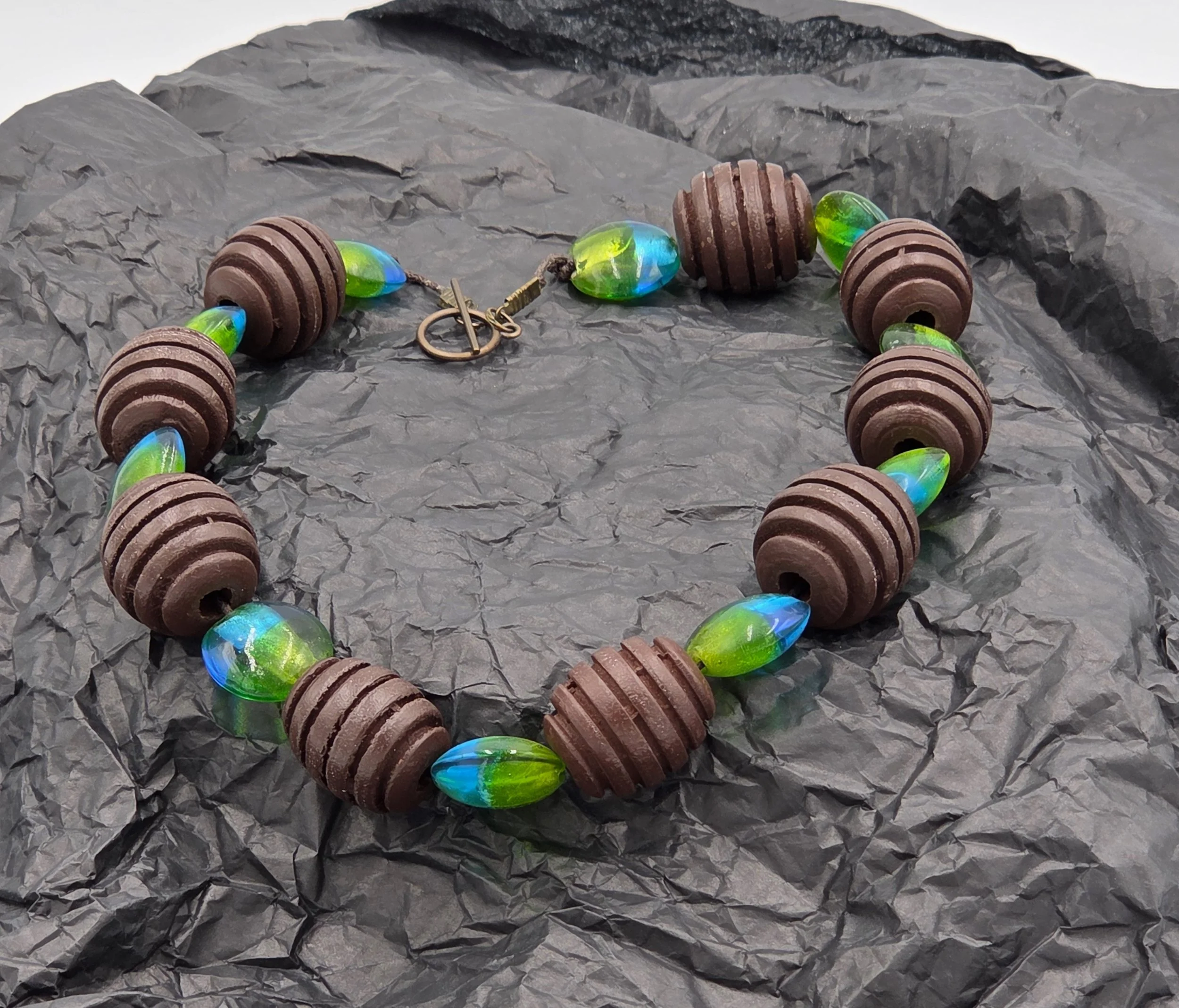 Choker necklace with large ribbed brown wood beads and blue-green foil glass beads.