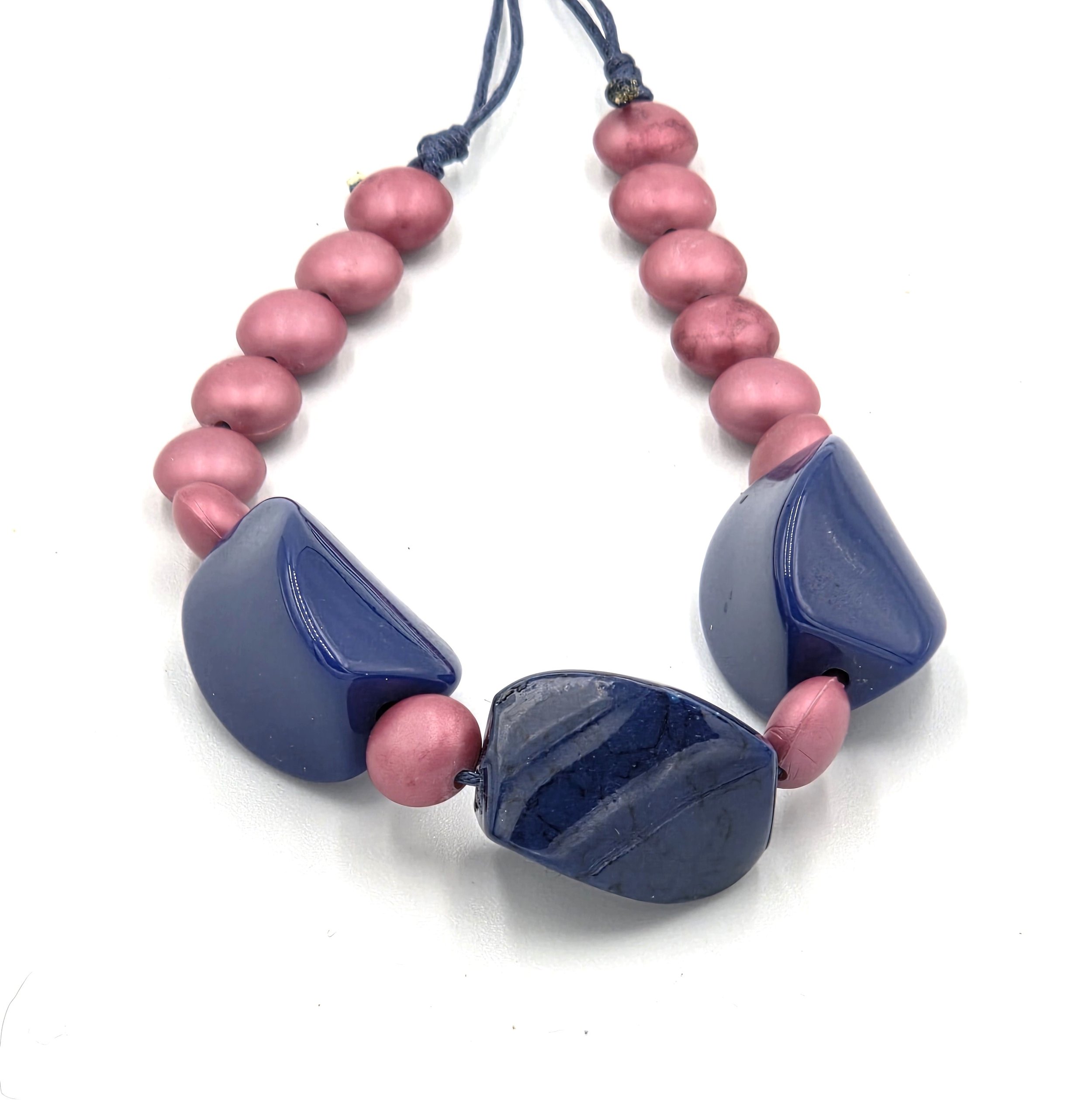 close up of Navy blue twisted bead necklace with matte pink accents on adjustable hemp cord.