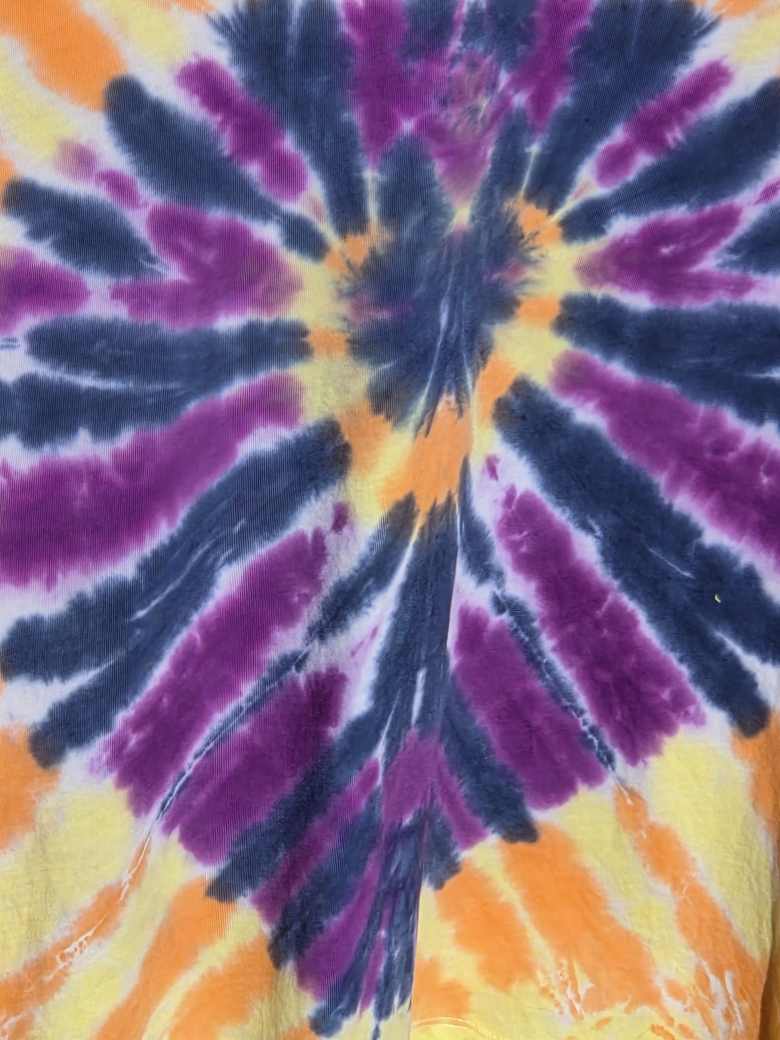 An adult size 14 women's cotton t-shirt featuring a tie-dye sunburst design in purple, dark blue, yellow, and orange.