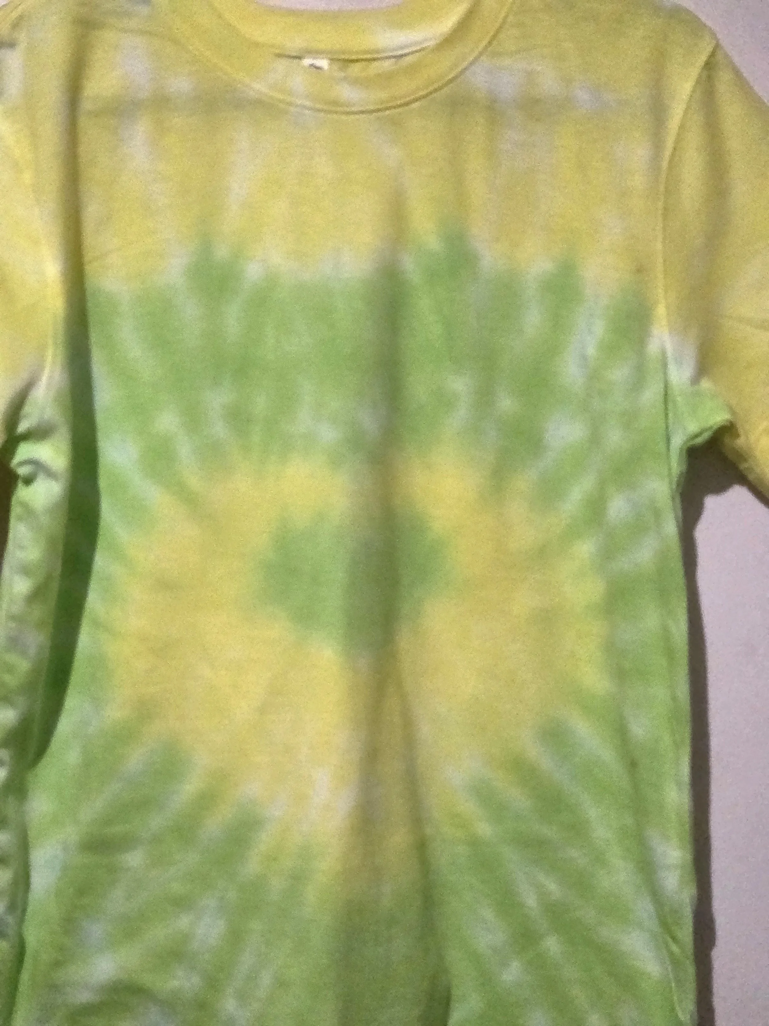 An adult size 10 women's cotton t-shirt featuring a tie-dye heart pattern in subtle pastel yellow and lime green.