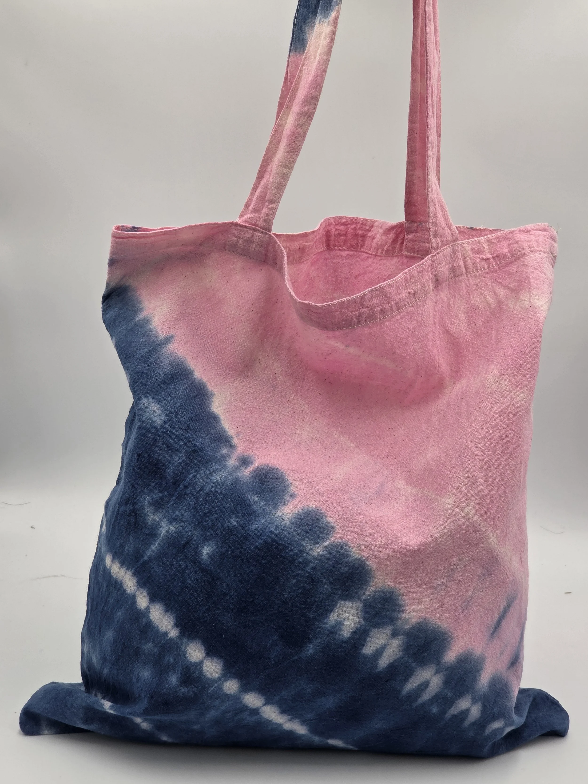 calico tote bag with a diagonal tie-dye split featuring pink on top and dark blue on the bottom with three batik resist lines.
