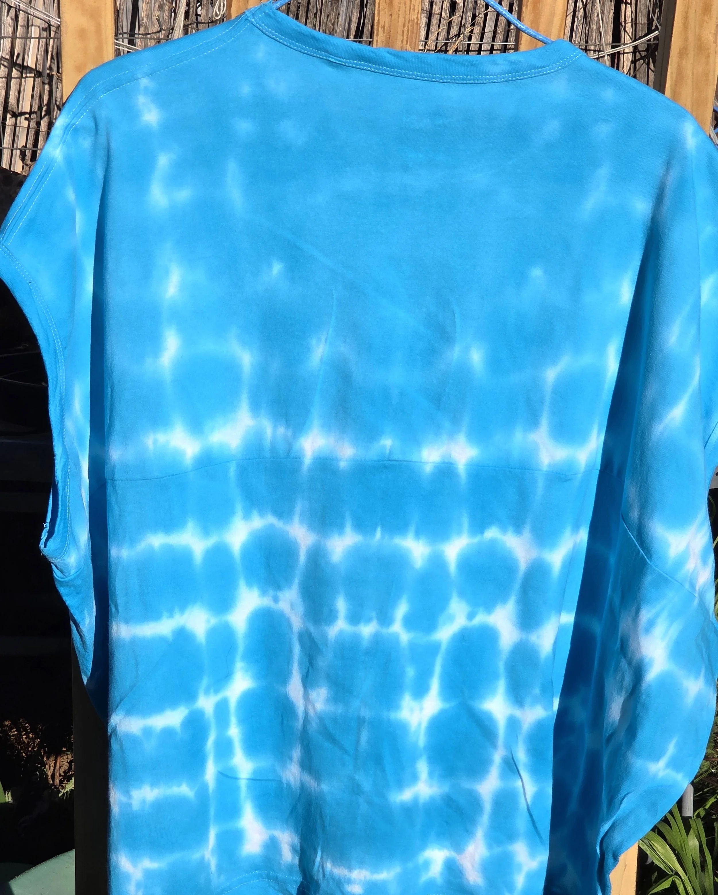 An adult size 12 women's oversized cotton t-shirt featuring a saturated turquoise tie-dye pattern with delicate horizontal white lines.