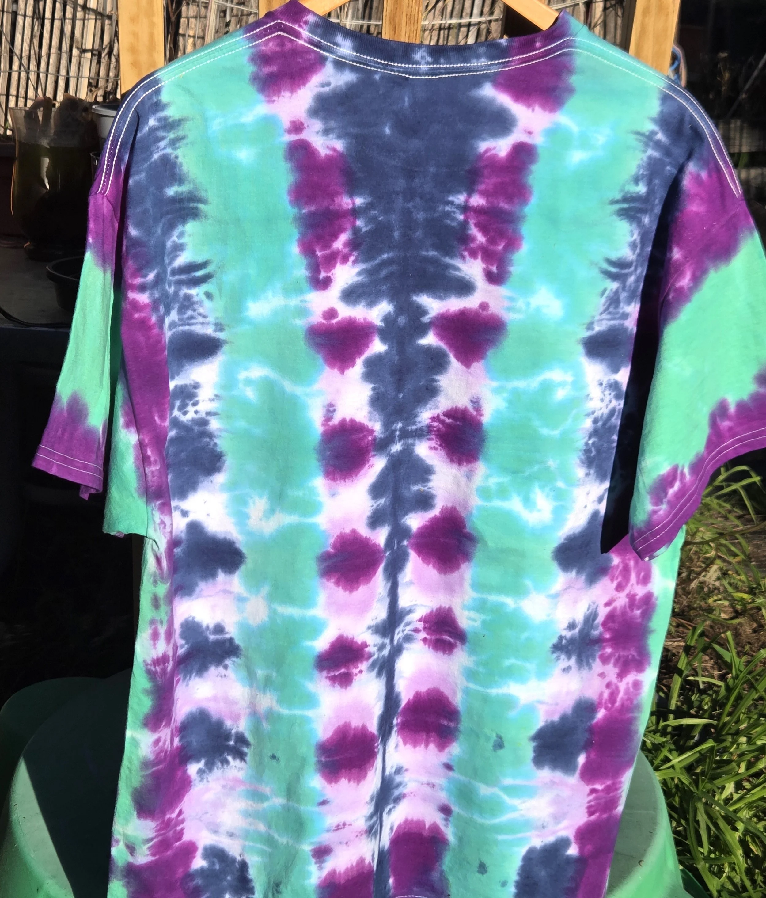 An adult size XL cotton t-shirt featuring vertical tie-dye columns in dark blue, purple, soft lilac, and solid teal green.