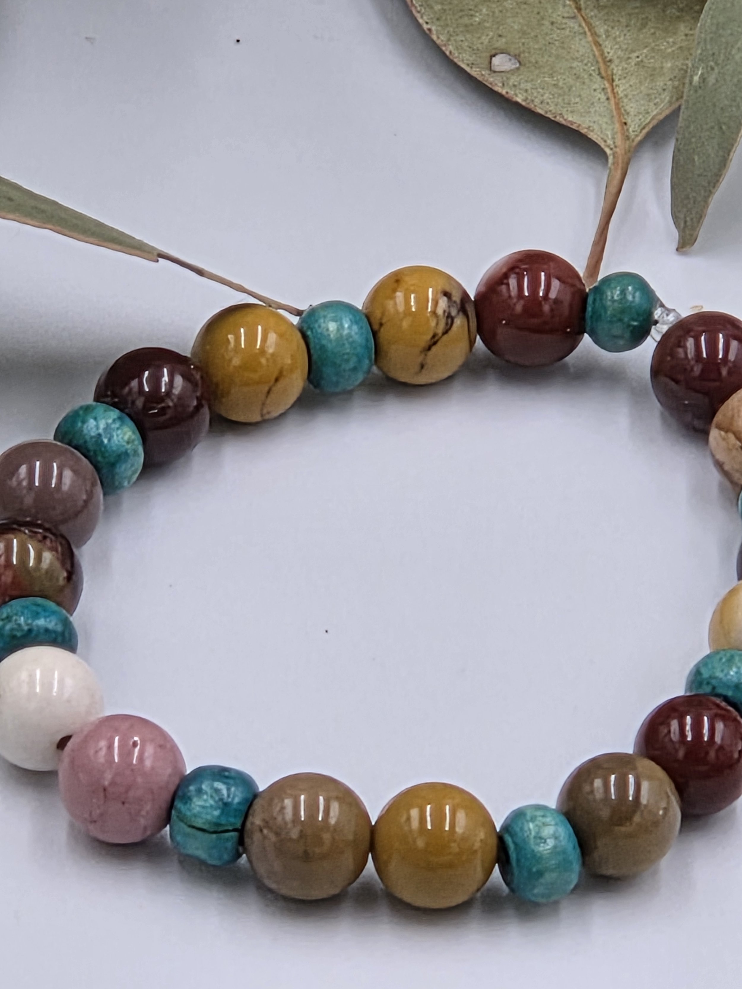 close up of Earth-toned cream and brown Mookaite jasper beads alternating with small sky blue wood beads on an elastic bracelet.