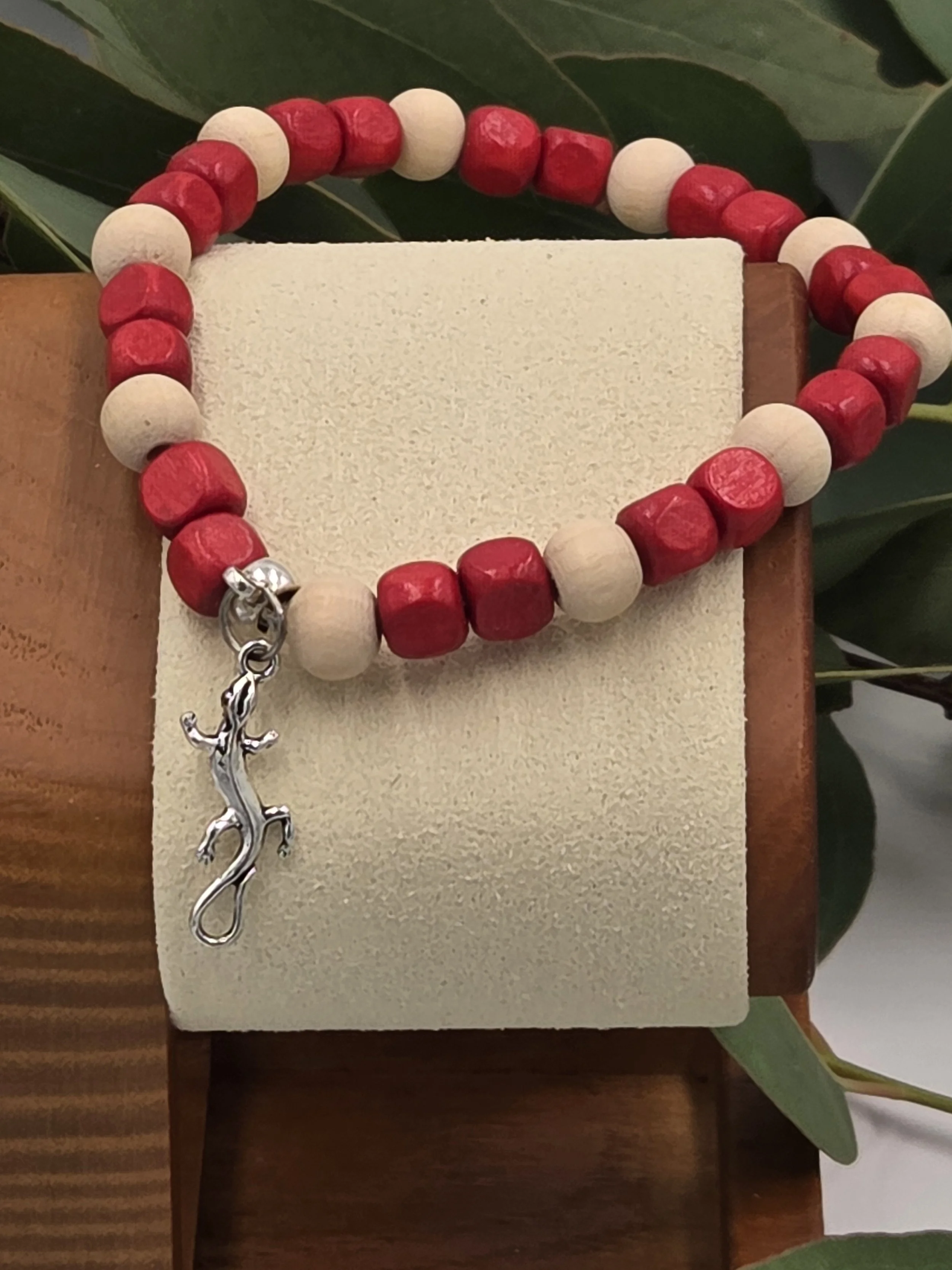 Close-up of Crimson Creeper bracelet on wooden stand showing geometric wood shapes.