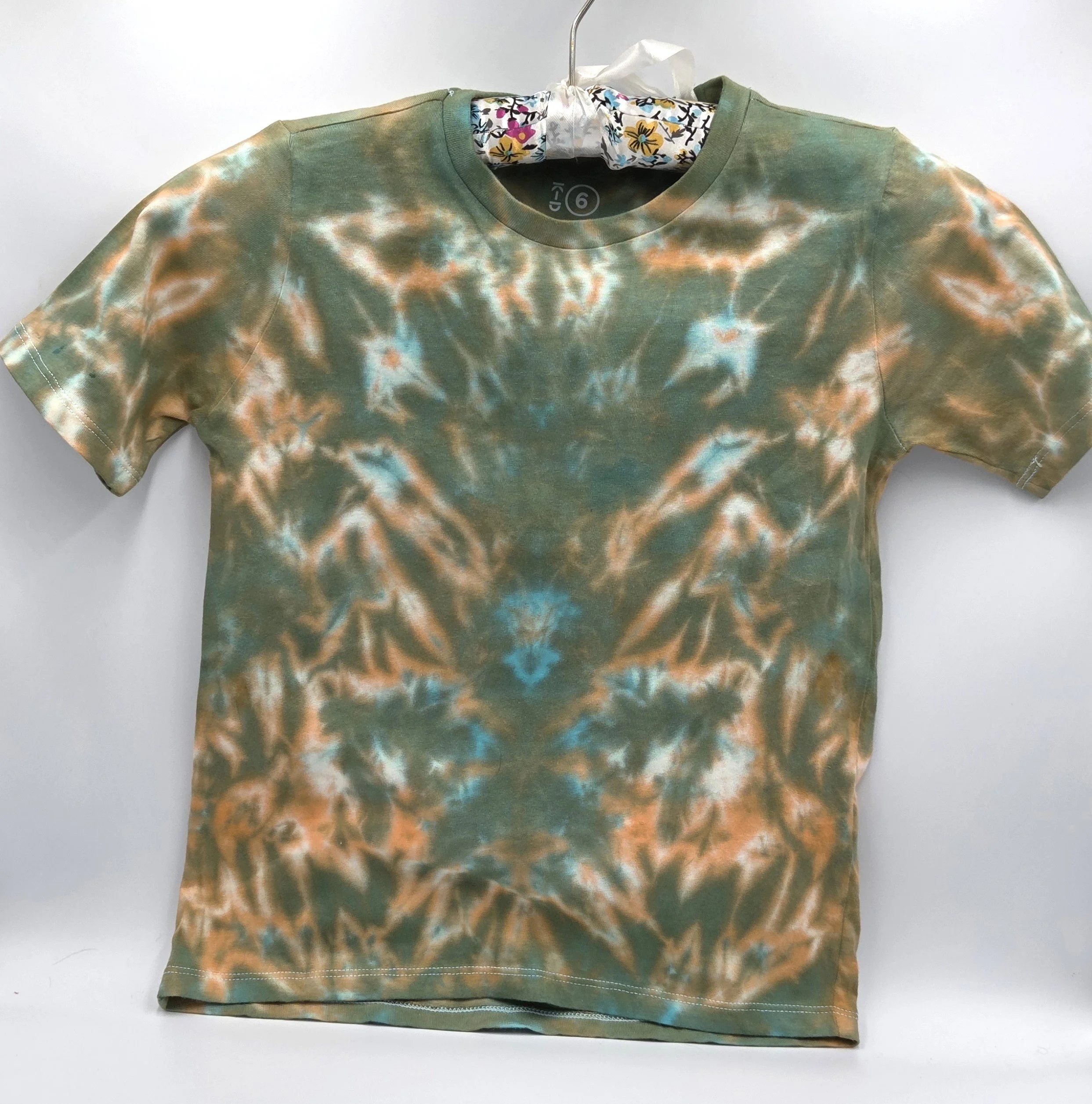 A child's size 6 t-shirt featuring a soft, pastel tie-dye tiger stripe pattern of khaki and orange with hints of sky blue.