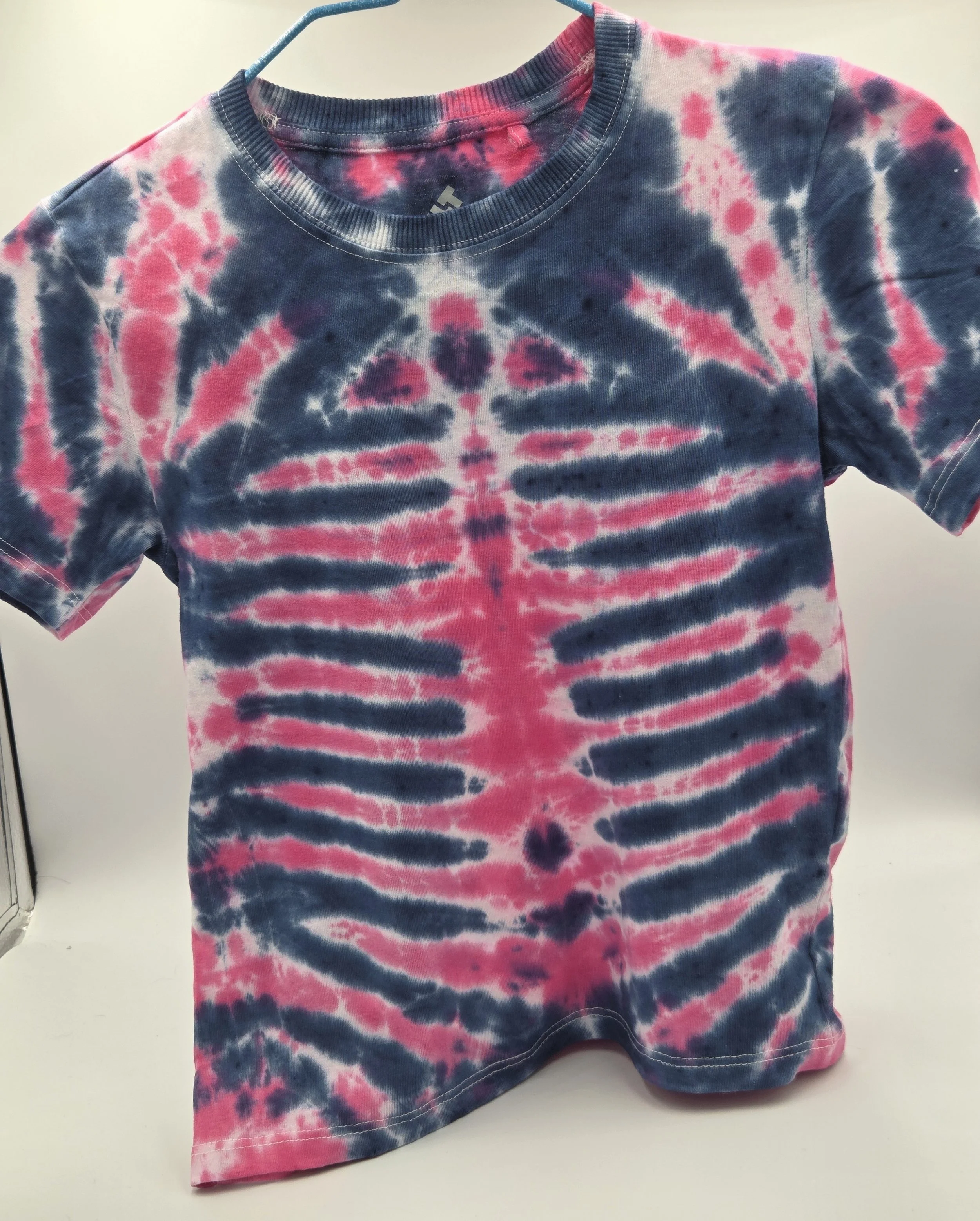 child size 7 cotton t-shirt featuring a fuchsia rib and spine tie-dye pattern against a dark blue background.
