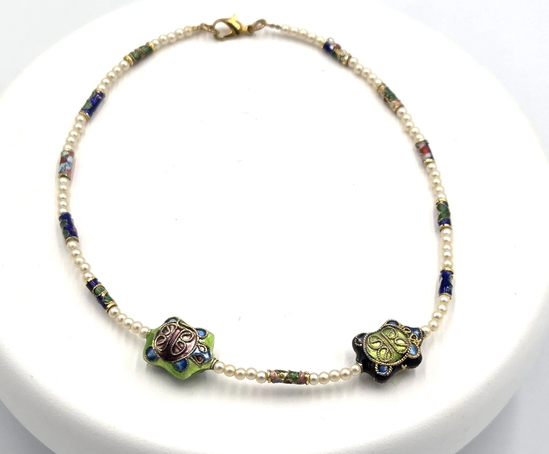 Petite white glass pearl necklace featuring colorful floral cloisonné tubes and two blue and green enamel sea turtles.