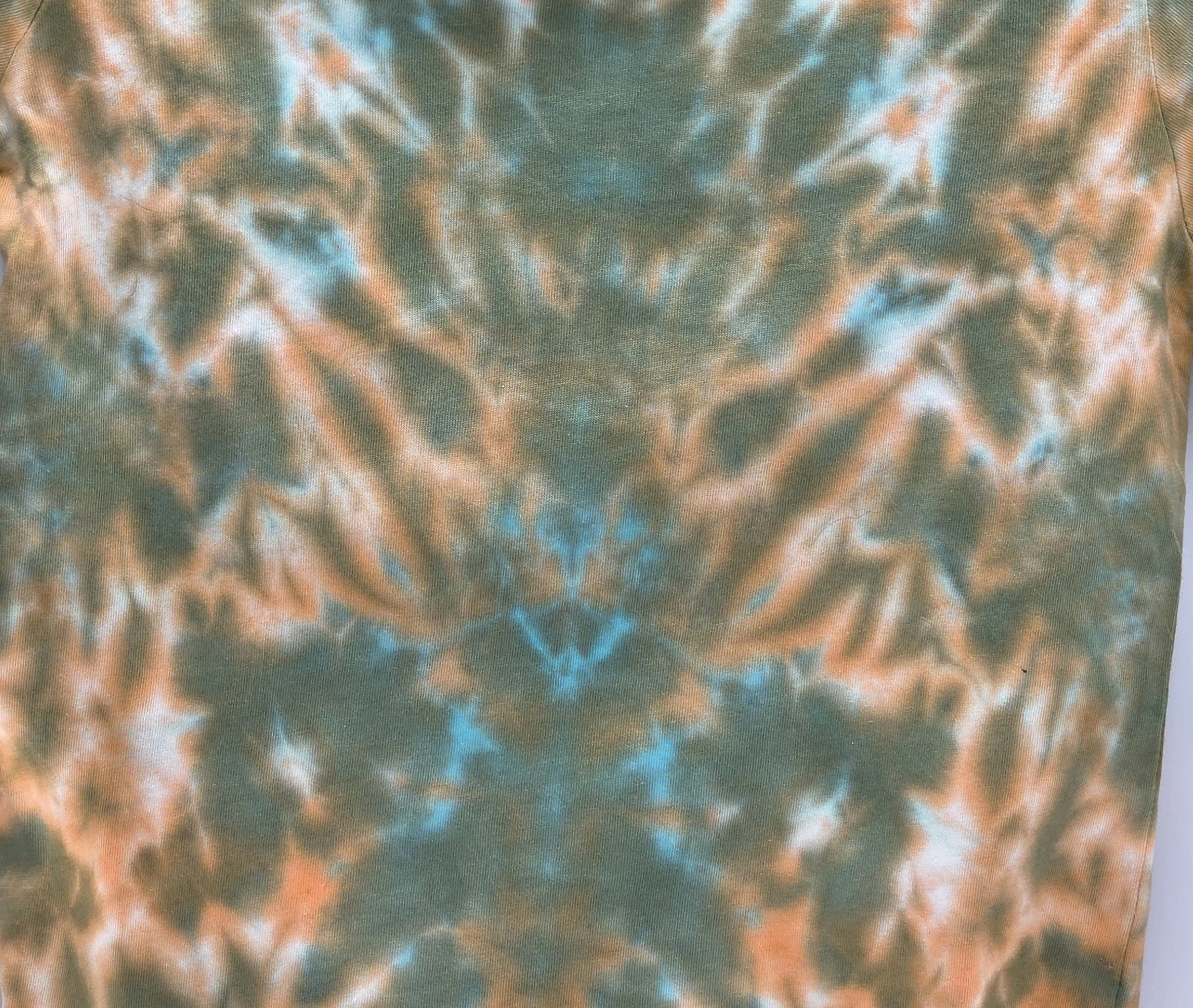 A child's size 6 t-shirt featuring a soft, pastel tie-dye tiger stripe pattern of khaki and orange with hints of sky blue.