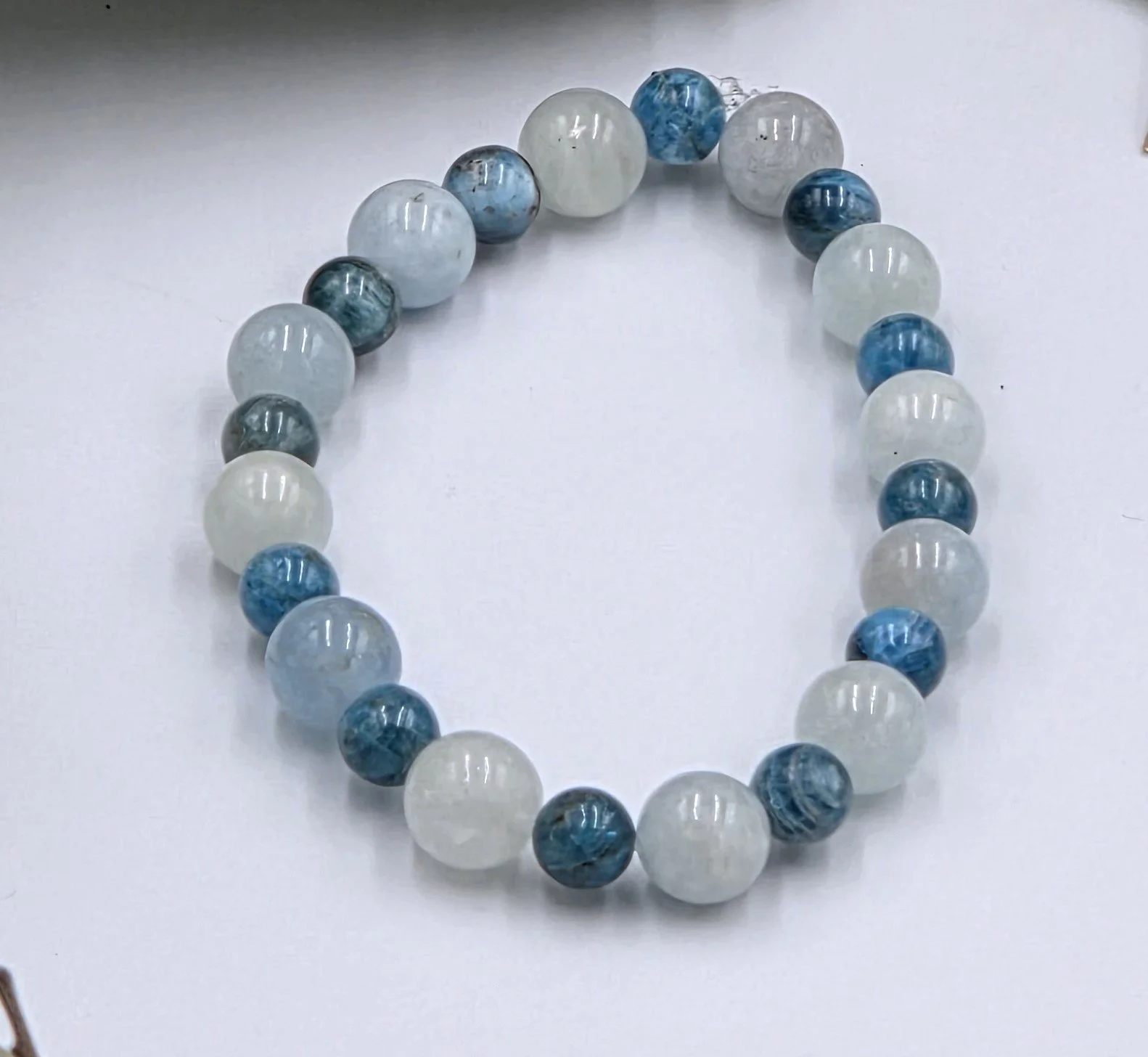 Alternating light blue-green Aquamarine beads and dark blue Apatite beads on an elastic gemstone bracelet.