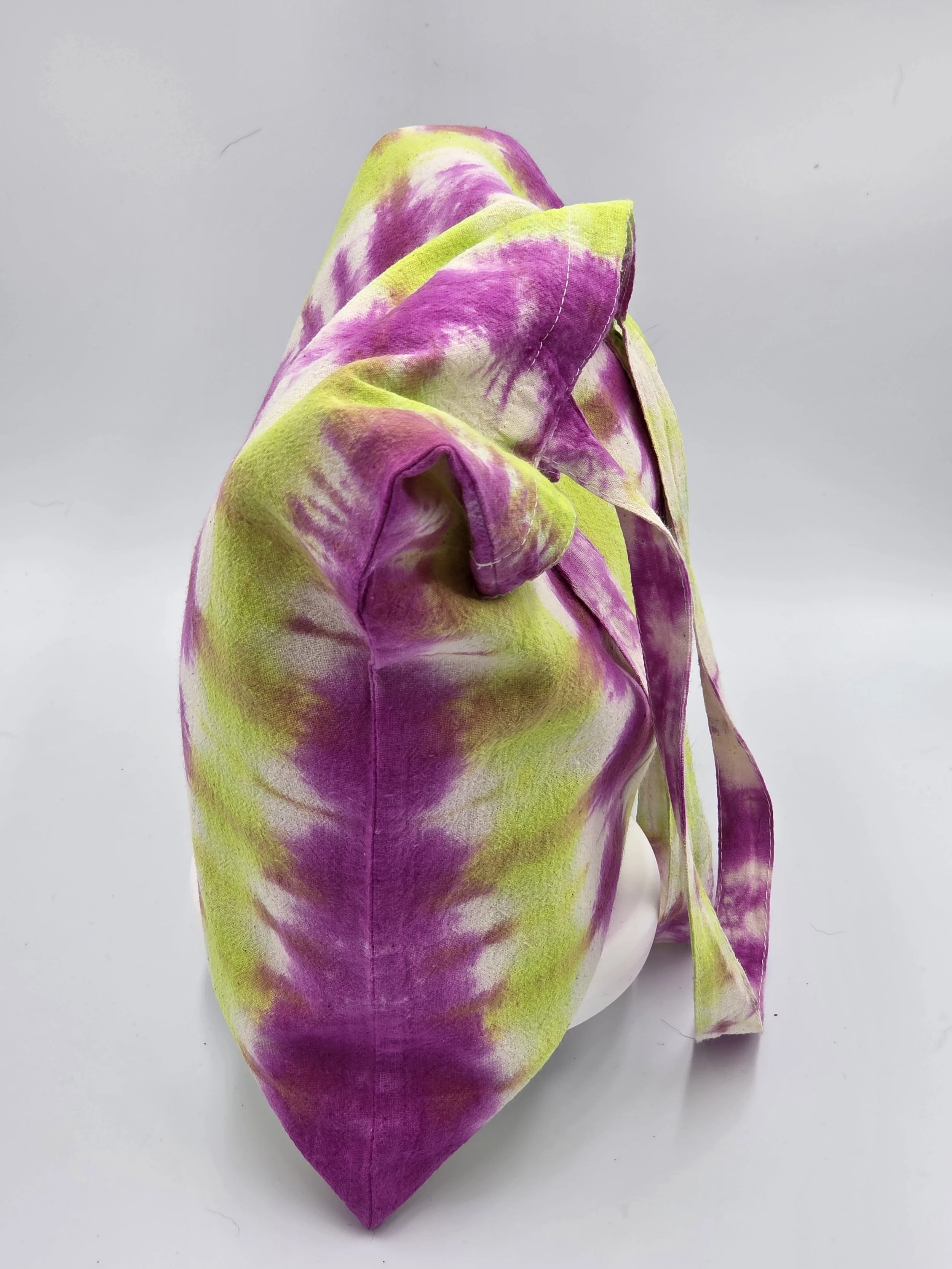 An upright, dimensional calico tote bag showcasing a vertical tie-dye pattern of rich fuchsia columns and bright lime green channels with hints of white.