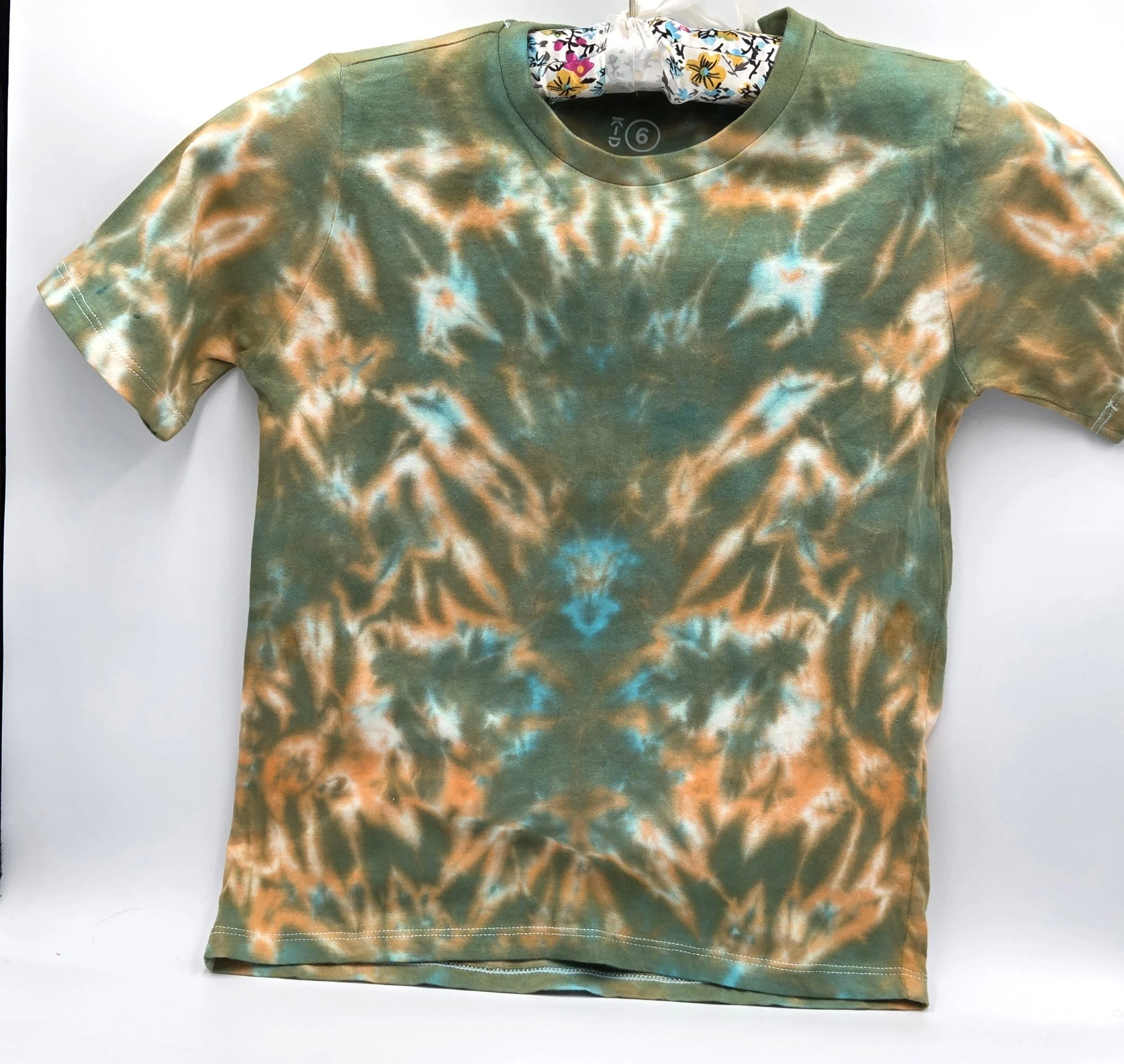 A child's size 6 t-shirt featuring a soft, pastel tie-dye tiger stripe pattern of khaki and orange with hints of sky blue.