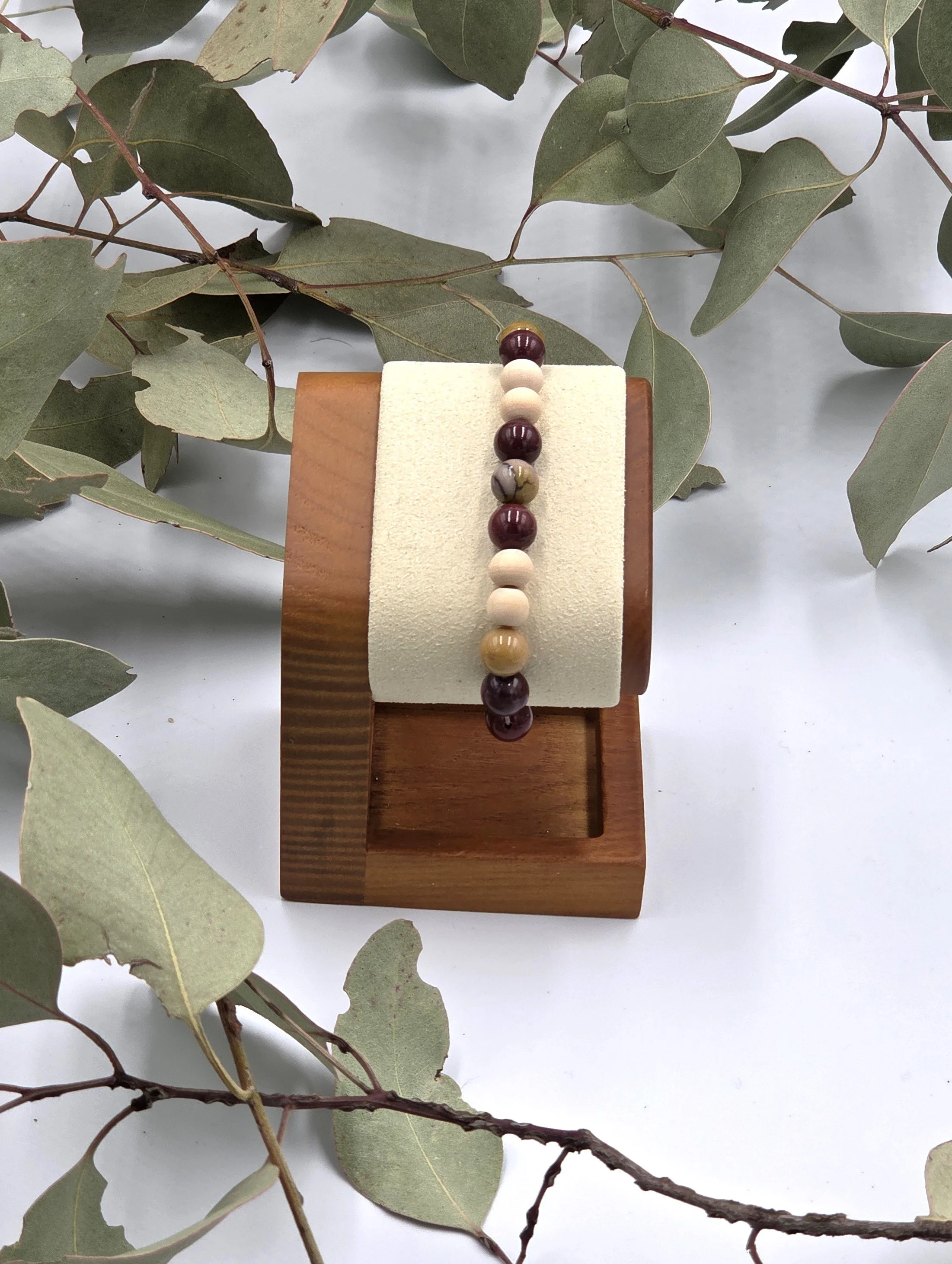 Earthy red and yellow Mookaite jasper beads alternating with small natural wood beads on an elastic bracelet.