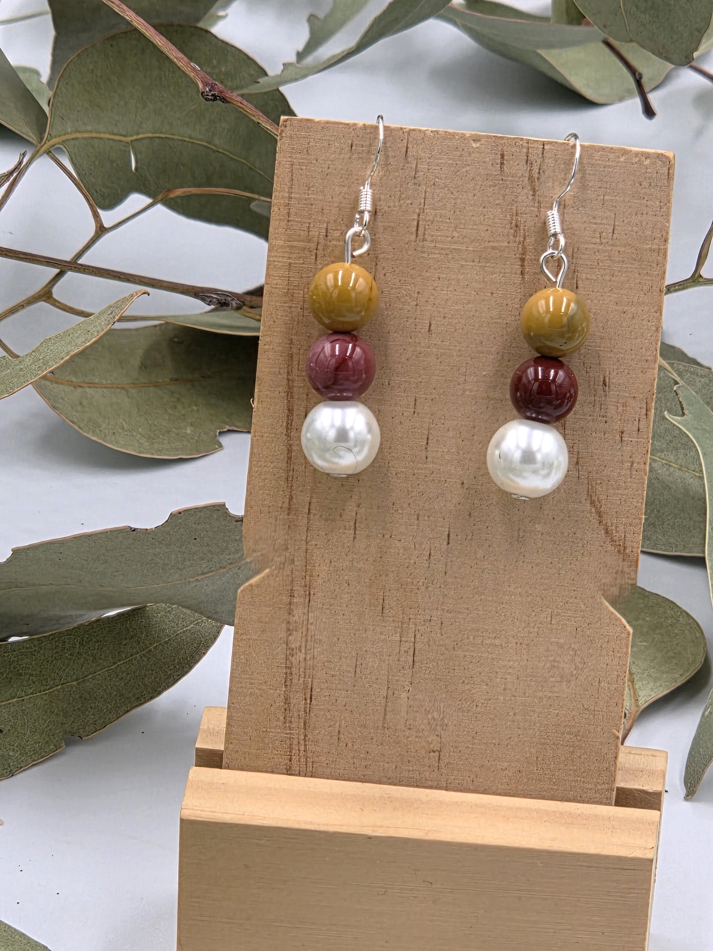 Brown and tan Mookaite beads topped with a white glass pearl on sterling silver dangle earring hooks.