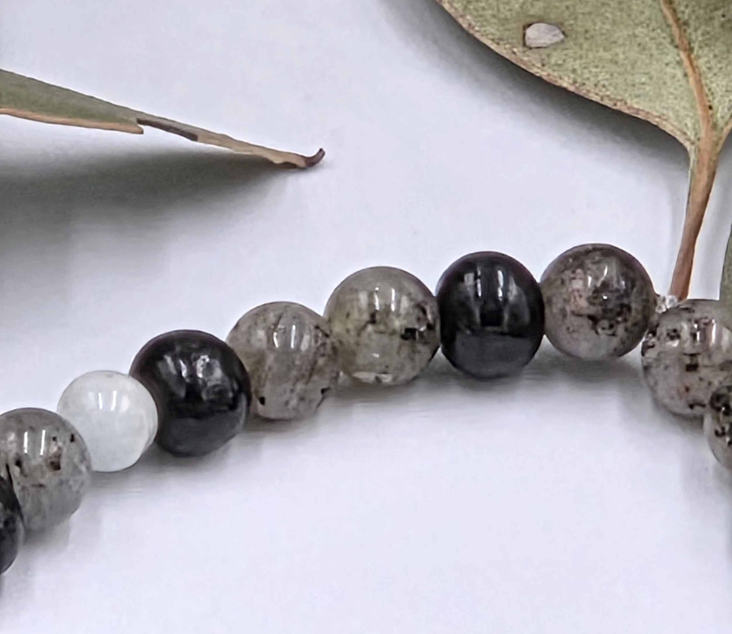 Grey Labradorite beads alternating in pairs with single black wood beads on an elastic bracelet.