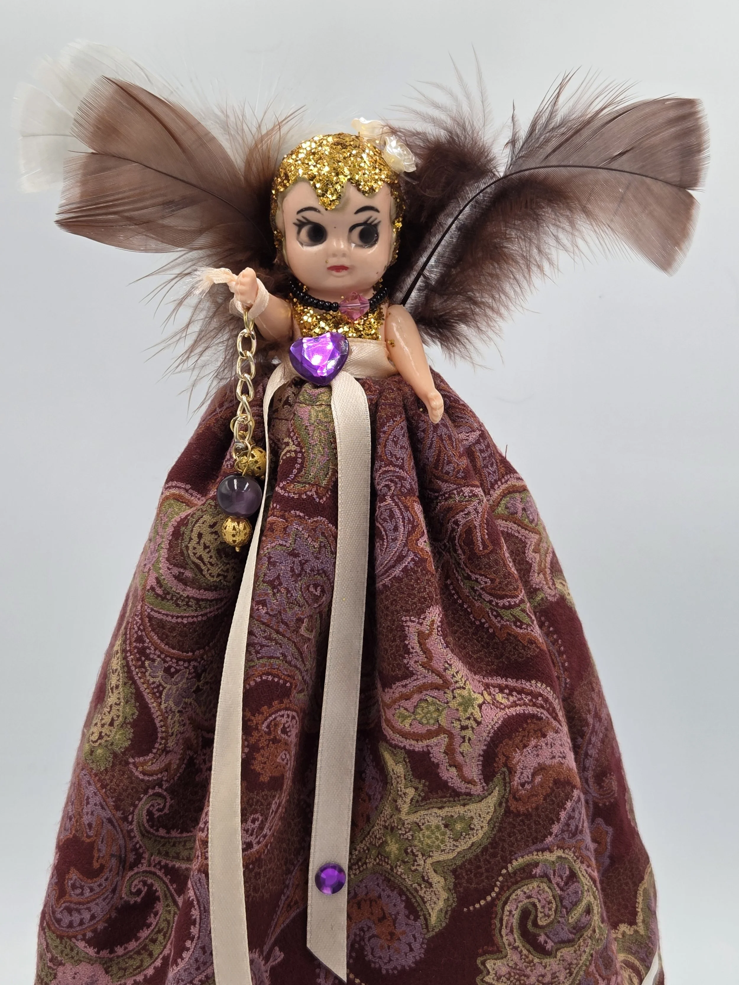 close-up Front view of Isadora Art Doll in burgundy paisley gown with white lace and feather surround.