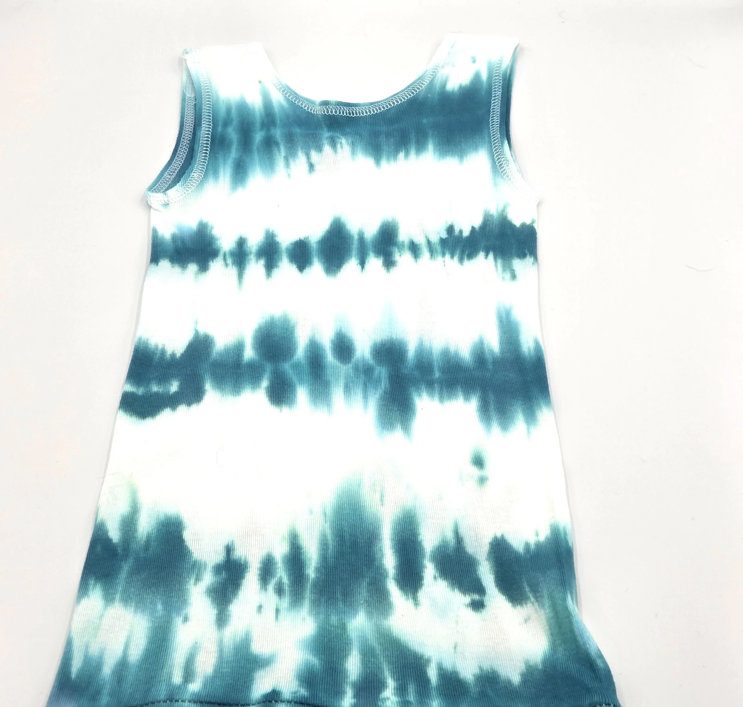 back view of child's white singlet displaying a vertical tie-dye pattern of deep sea green wave lines.