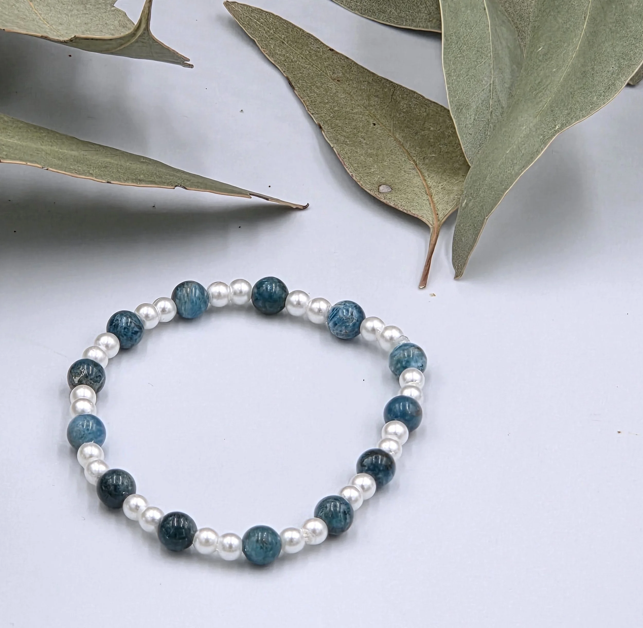 Deep blue Apatite beads alternating with small glossy white glass pearls on a delicate elastic bracelet.