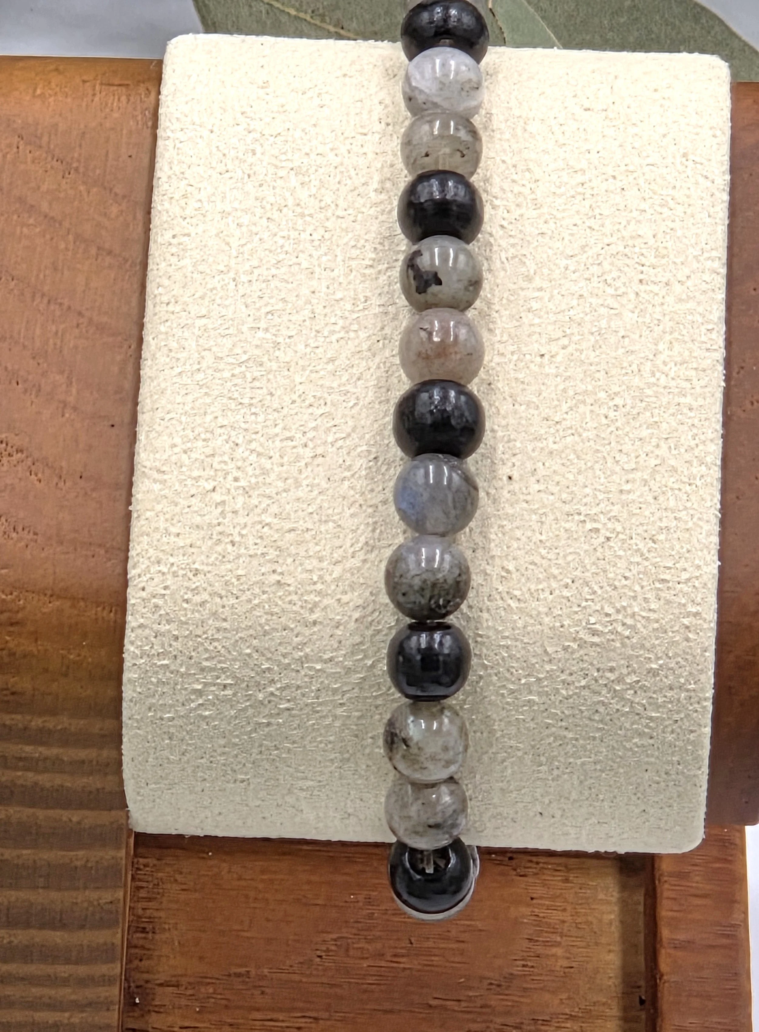 Grey Labradorite beads alternating in pairs with single black wood beads on an elastic bracelet.