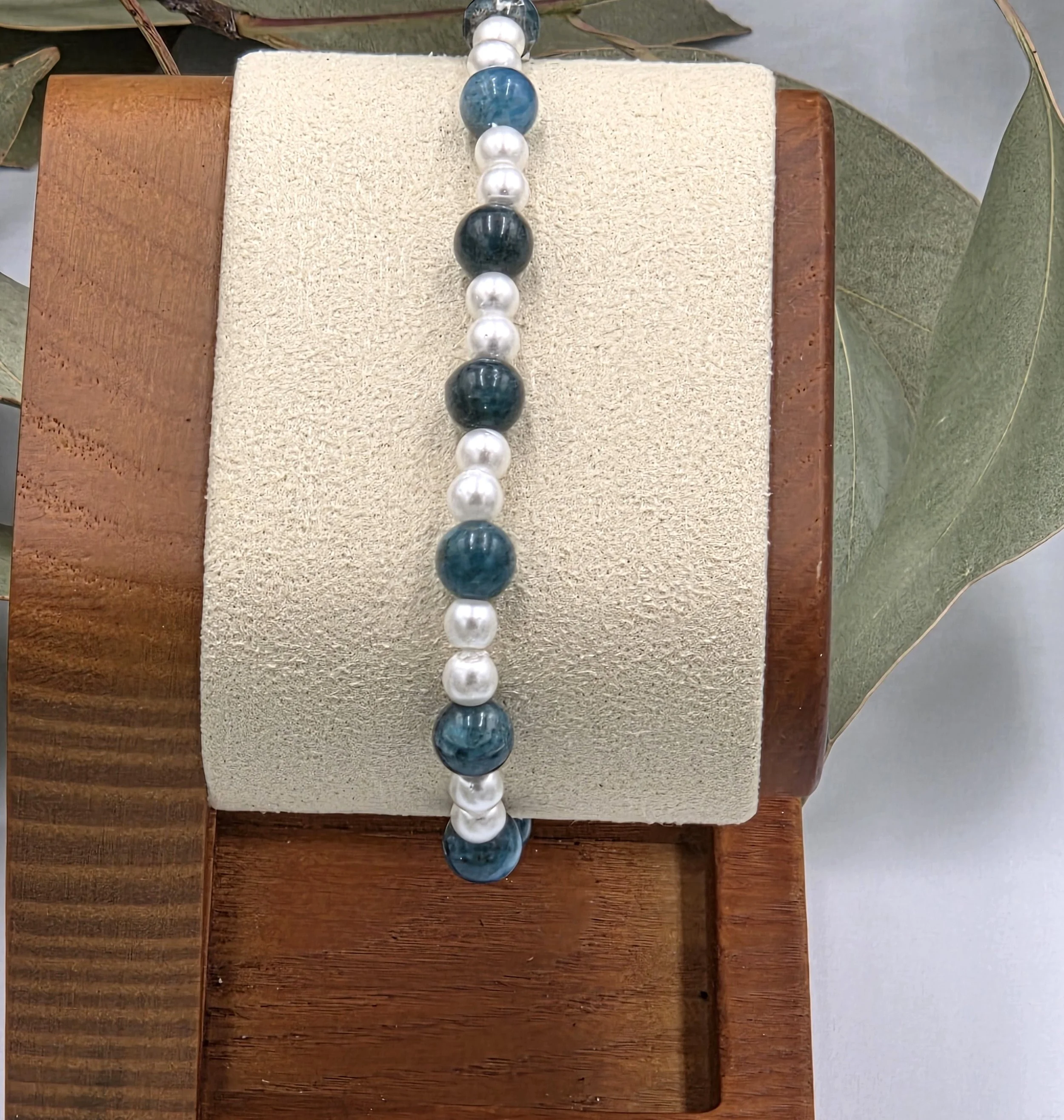 Deep blue Apatite beads alternating with small glossy white glass pearls on a delicate elastic bracelet.