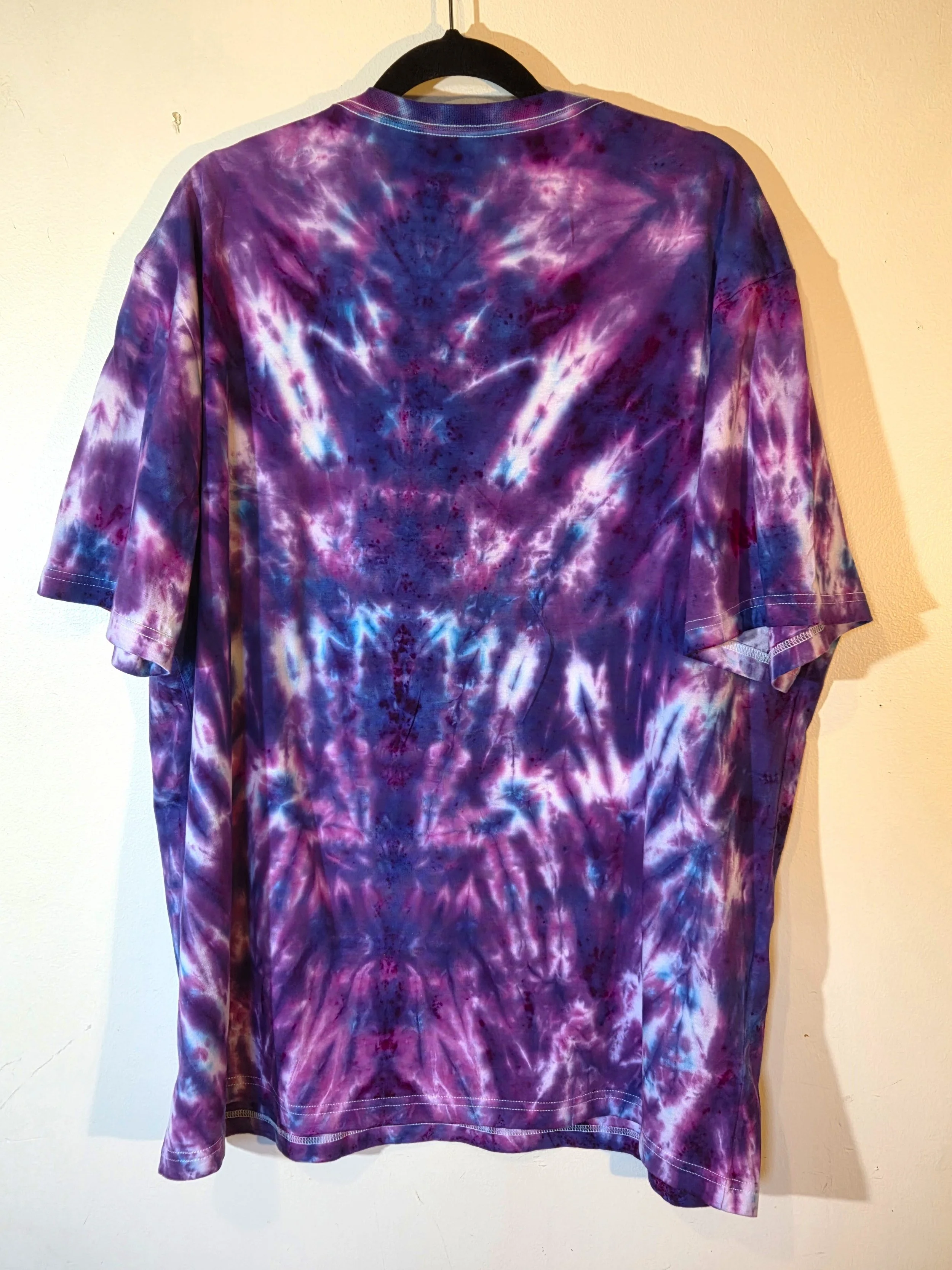An adult XXL t-shirt featuring an intense red and burgundy tie-dye pattern that shapes a narrow fan at the neck and expands into a horizontal psychedelic design near the hem.