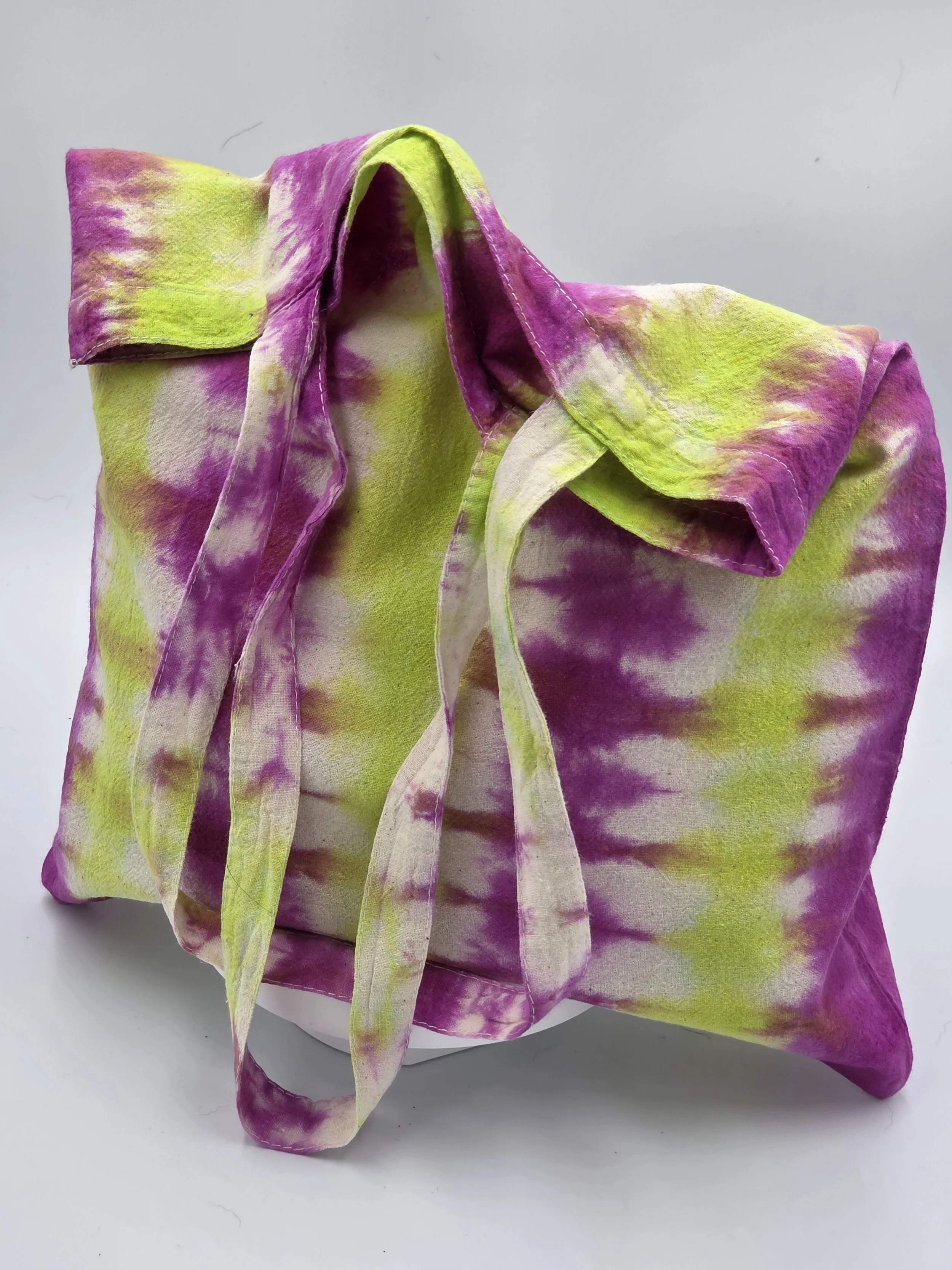 An upright, dimensional calico tote bag showcasing a vertical tie-dye pattern of rich fuchsia columns and bright lime green channels with hints of white.