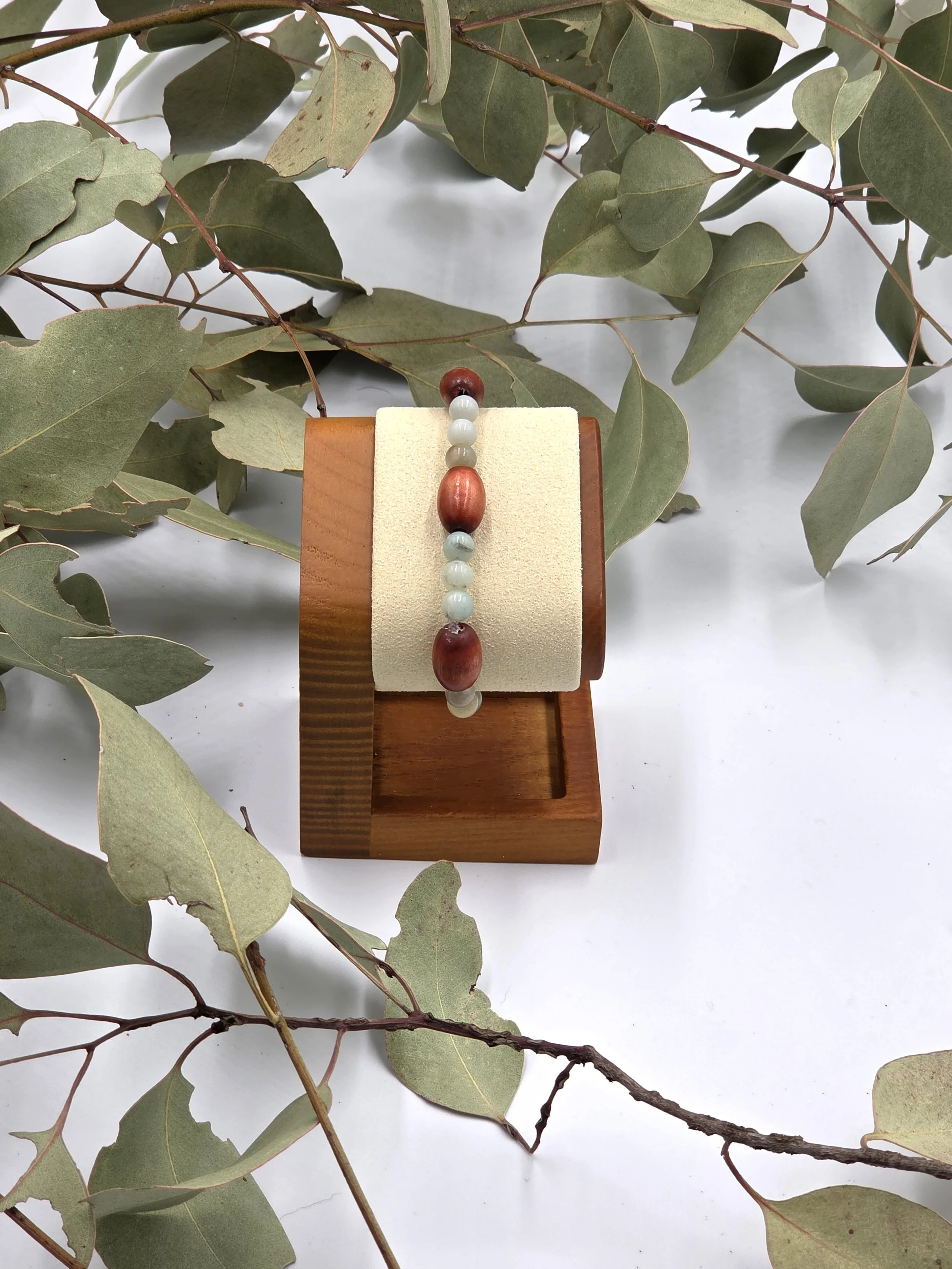 Smooth green Amazonite beads alternating in sets of three with single large brown oval wood beads on an elastic bracelet.