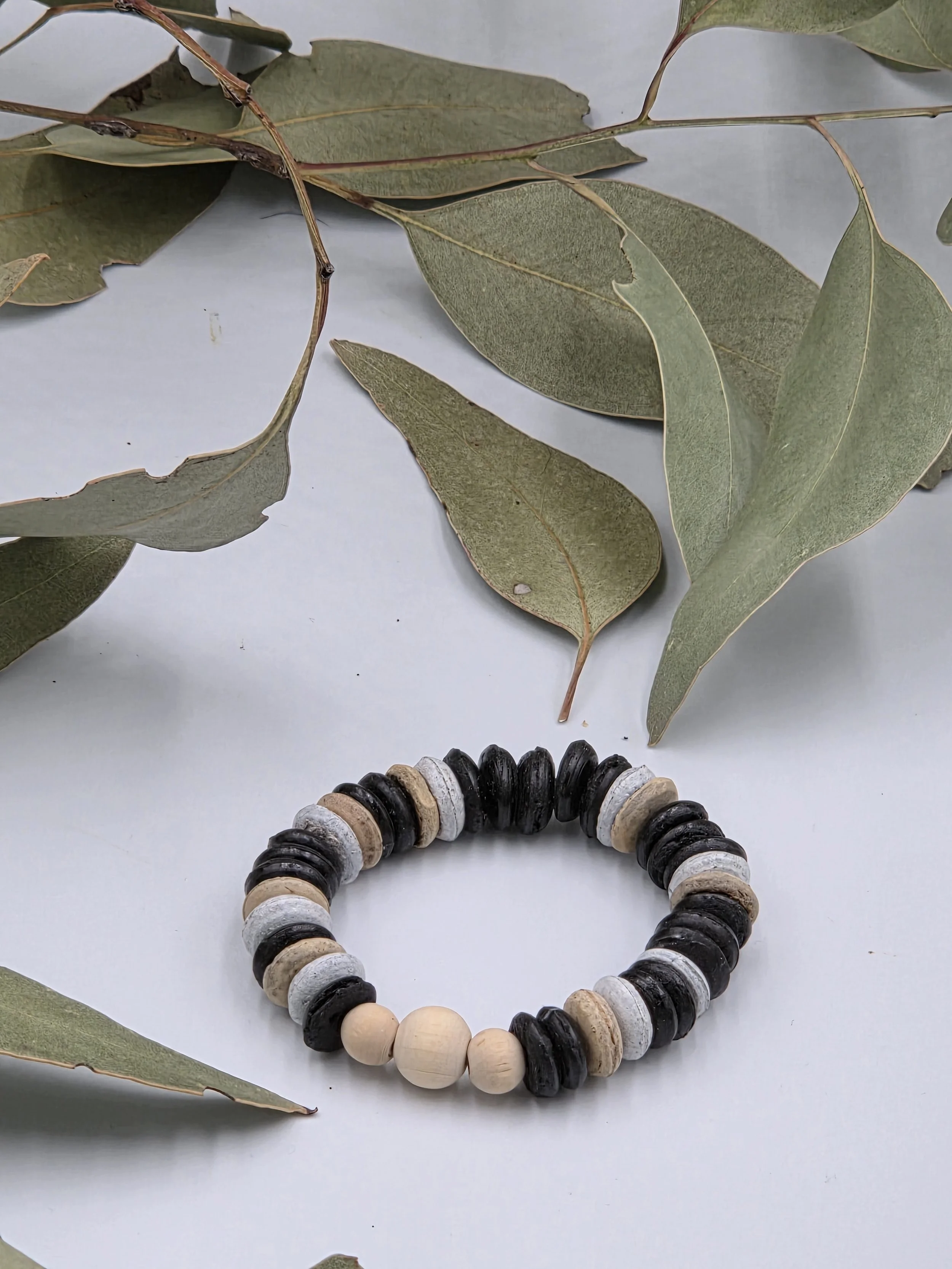 Striped brown and white coconut disc bracelet featuring a small trio of raw natural wood beads as a central focal point.