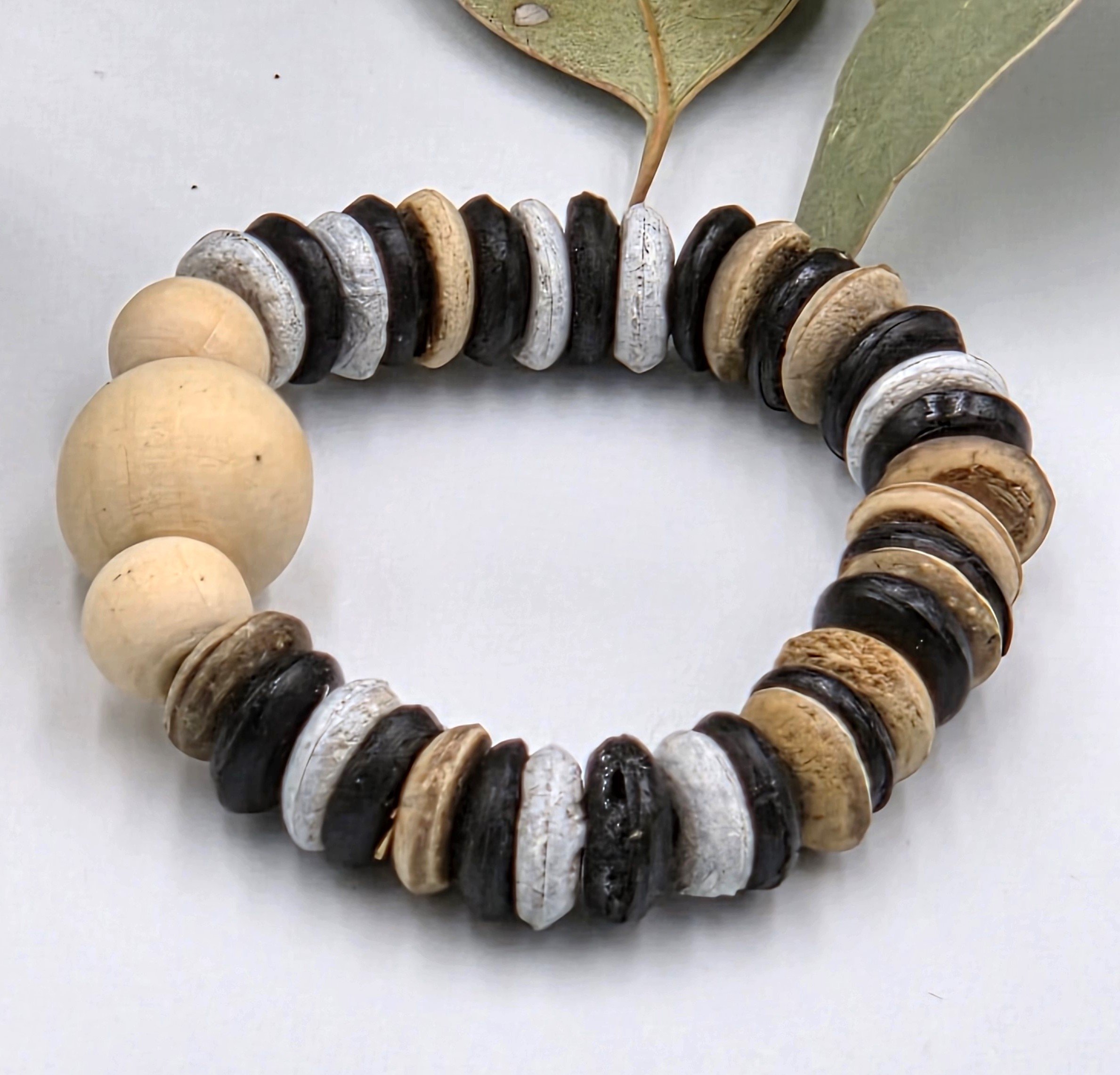 Striped brown and white coconut disc elastic bracelet featuring raw natural wood beads as a central focal point.