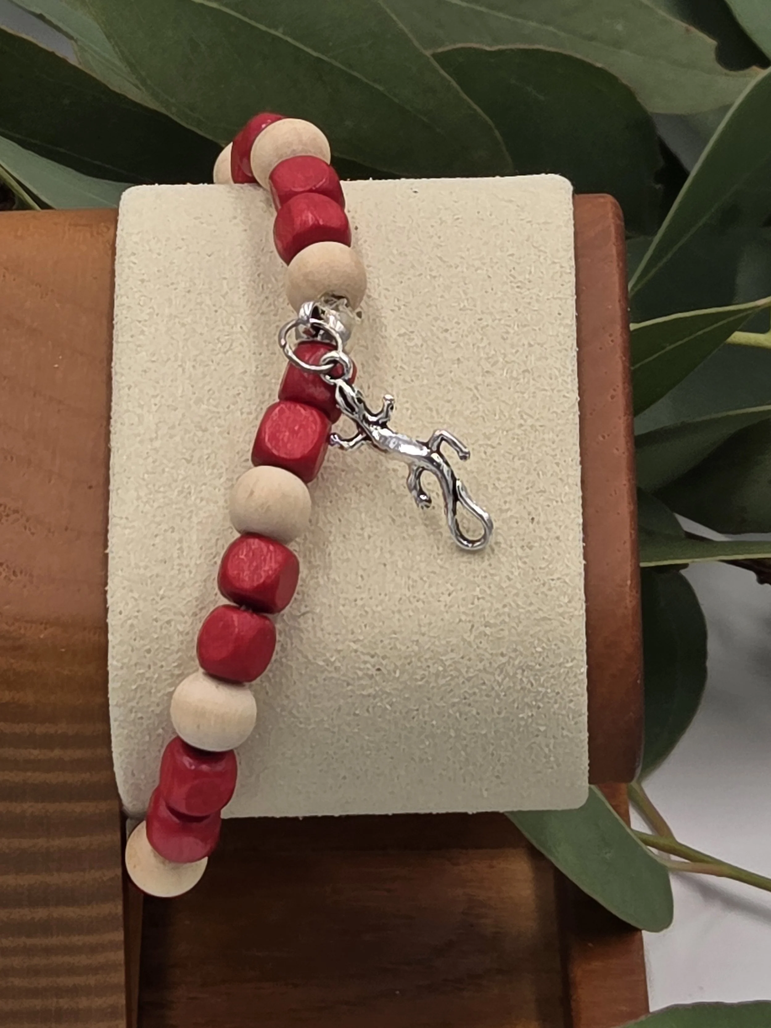 Close-up of Crimson Creeper bracelet on wooden stand showing geometric wood shapes.