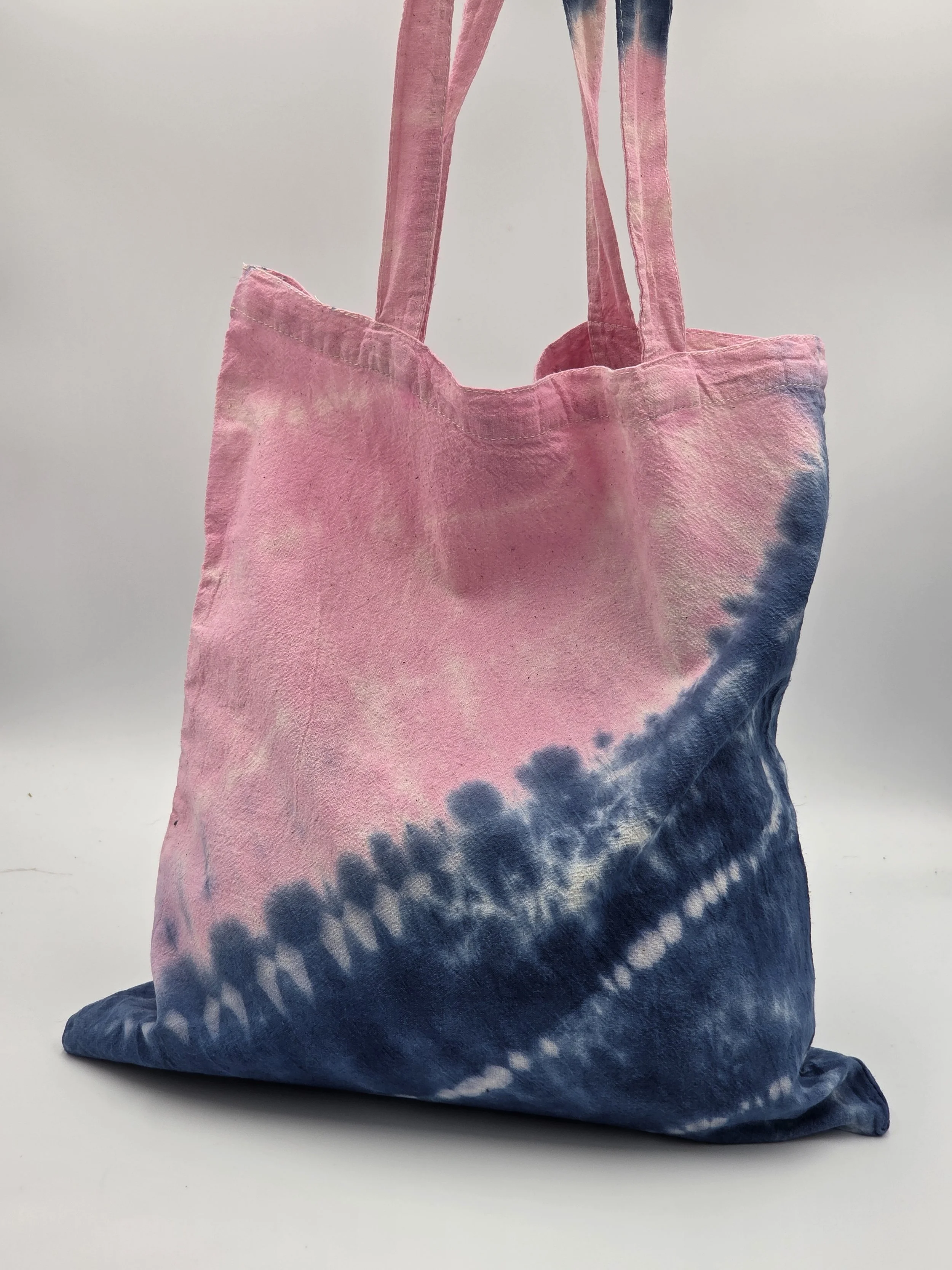 calico tote bag with a diagonal tie-dye split featuring pink on top and dark blue on the bottom with three batik resist lines.
