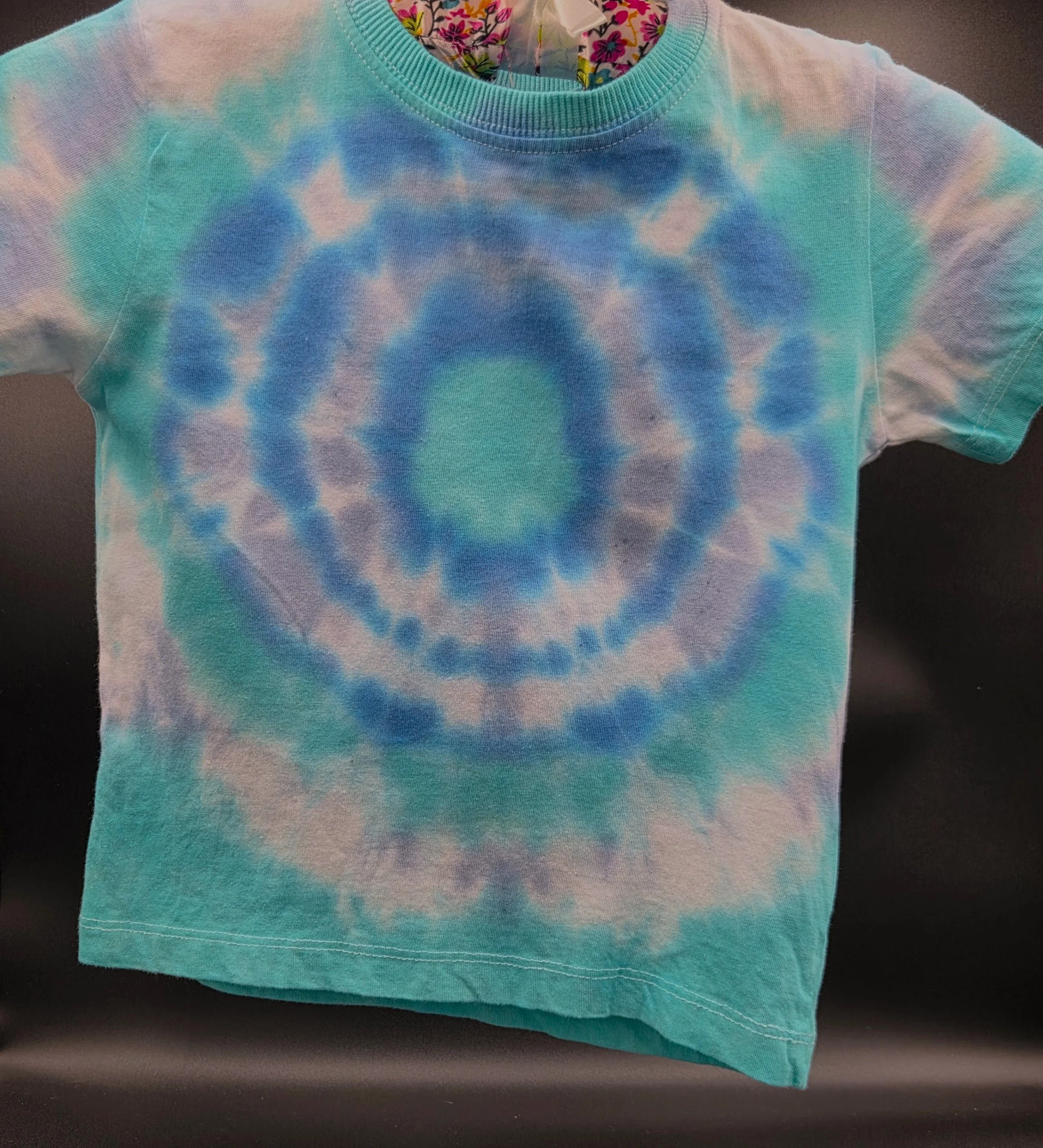 Child's size 4 hand-dyed 100% cotton T-shirt featuring a blue, green, and white concentric bullseye pattern. One-of-a-kind wearable art by Livity Studio Canberra.