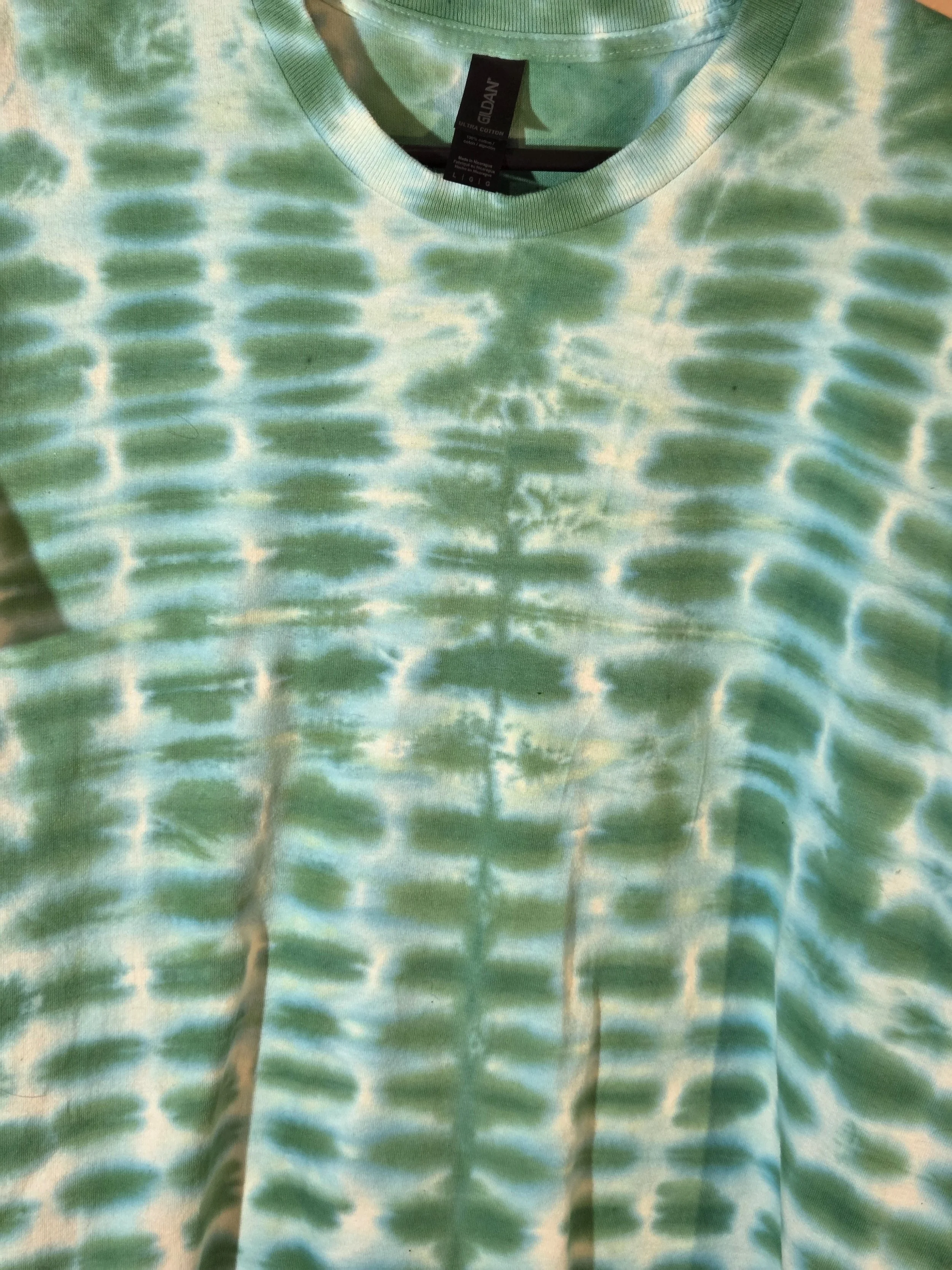 close up of A large adult green and white t-shirt featuring a highly regular tie-dye pattern resembling green bricks in a wall.