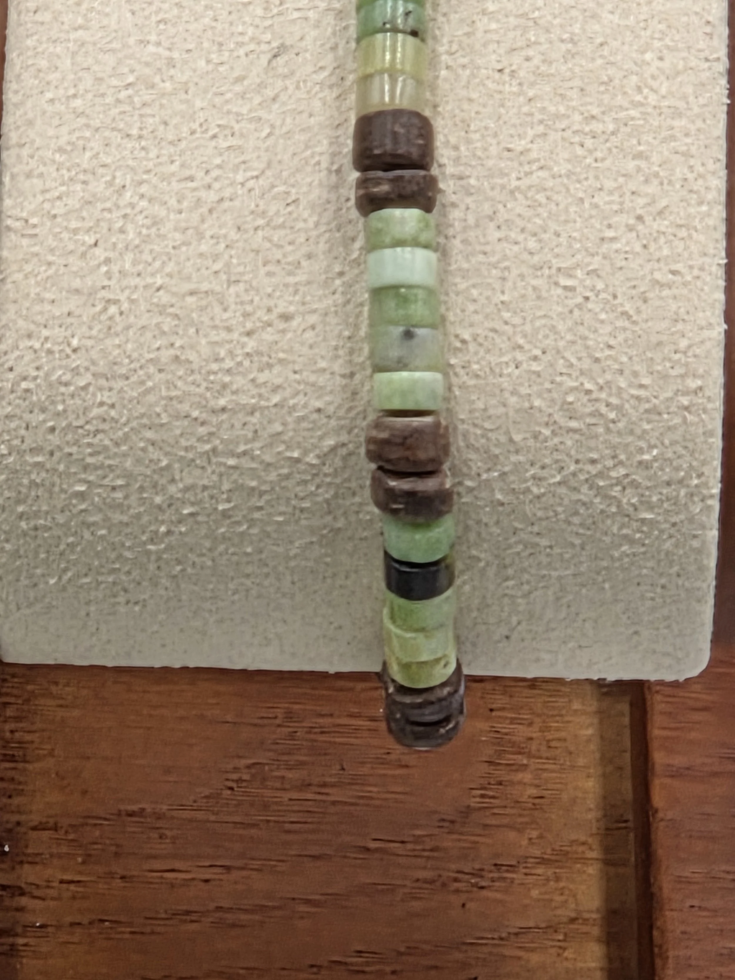 Very small green chrysoprase discs alternating in groups of five with pairs of brown coconut discs on a delicate elastic bracelet.
