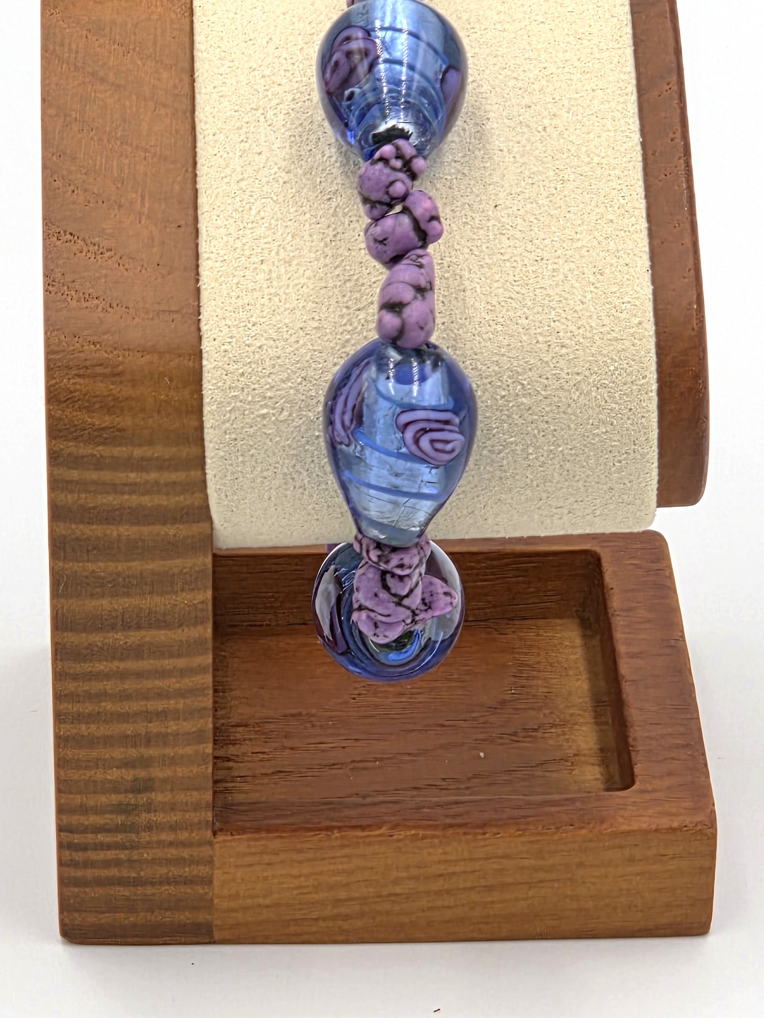 close up of Elastic bracelet with large striped glass beads featuring pink roses and purple stones.