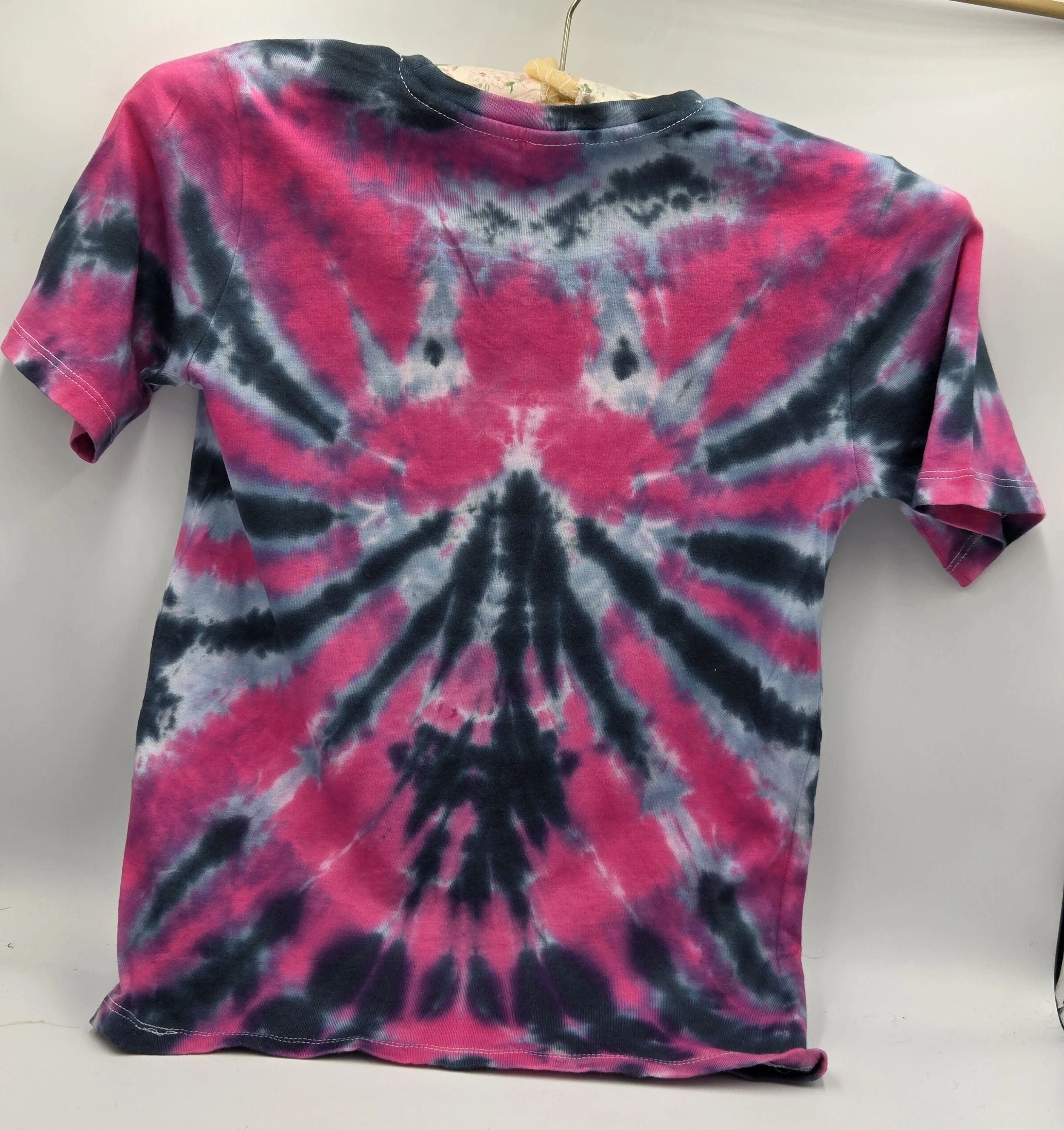 A child size 7 cotton t-shirt featuring a dramatic fuchsia and black spider tie-dye pattern with soft grey accents.